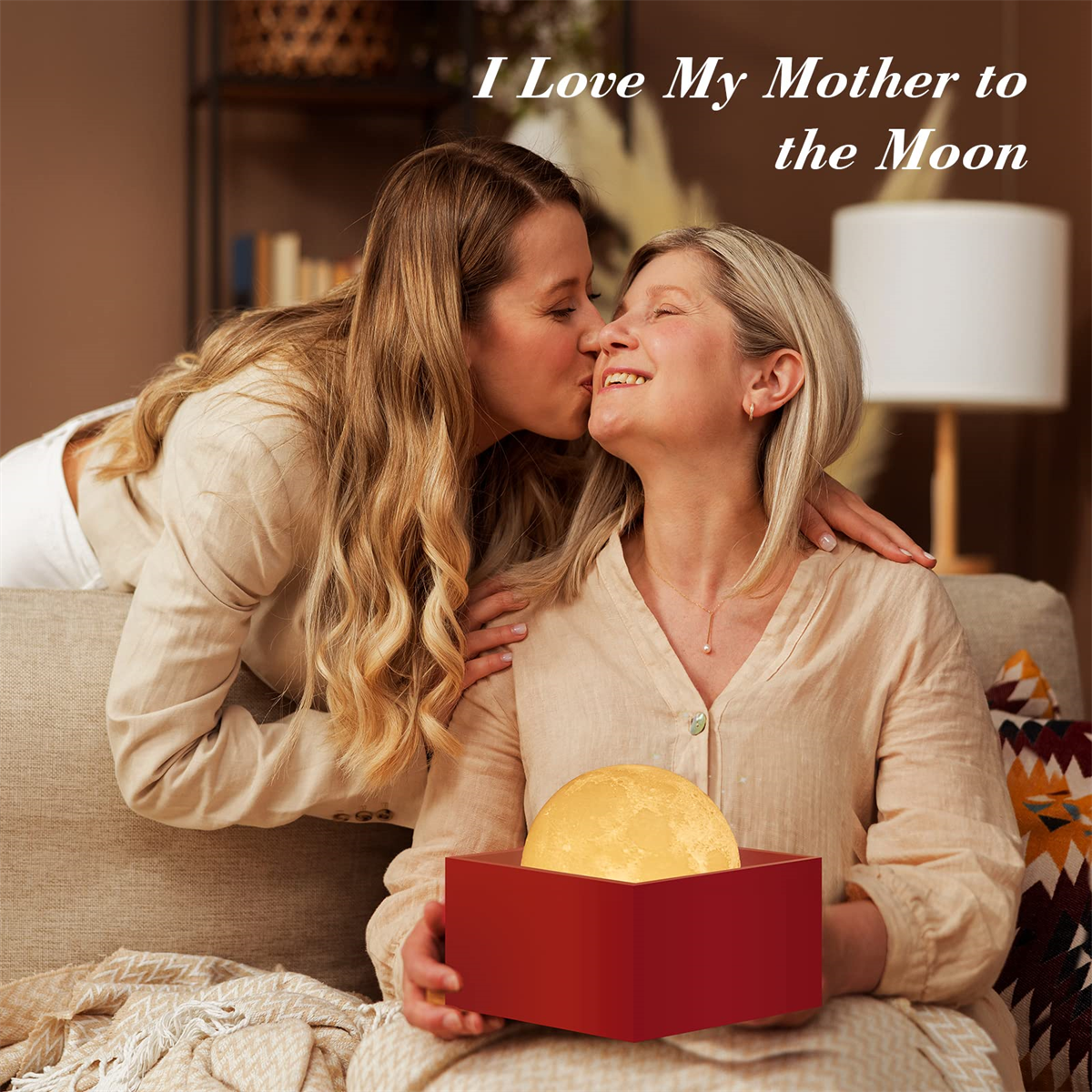 Eine Frau küsst eine andere, die eine Box mit einer Mondlampe hält. Text: Ich liebe meine Mutter.