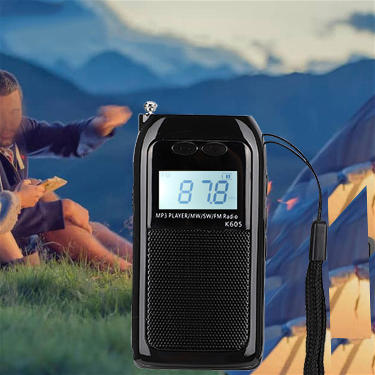 Schwarzes Radio mit Digitalanzeige. Eine Person sitzt im Hintergrund auf Gras in der Nähe von Zelten.