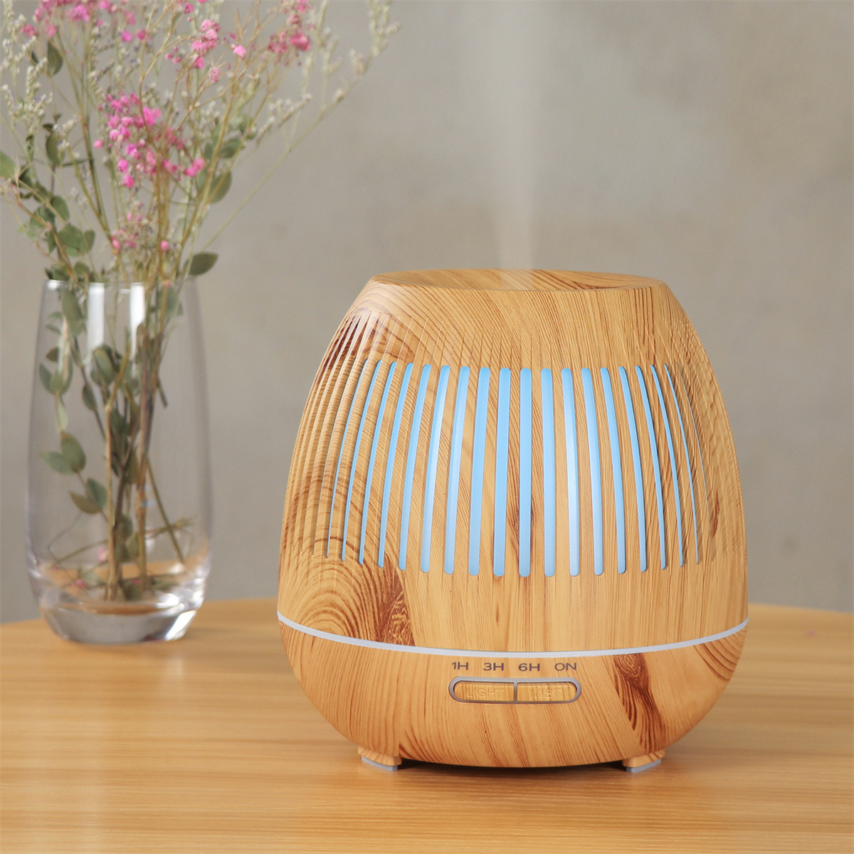 Diffusor für ätherische Öle mit Holzmaserung und Blumenvase auf dem Tisch.