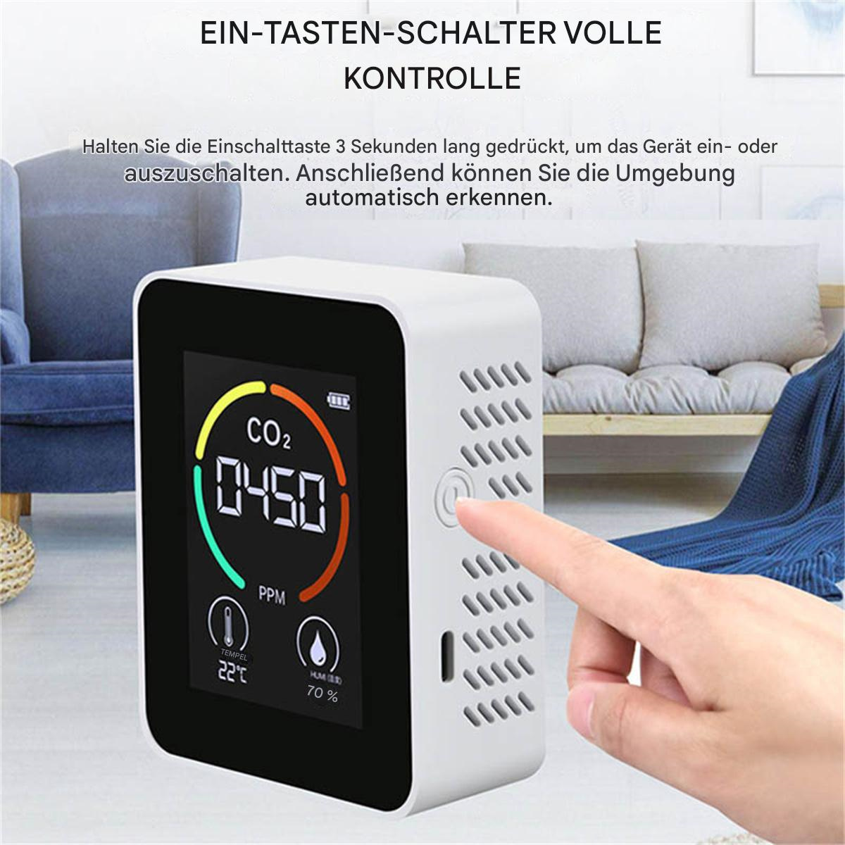 Ein weißes Gerät mit CO2-Anzeige, Temperatur und Luftfeuchtigkeit, und ein Finger, der einen Knopf drückt.