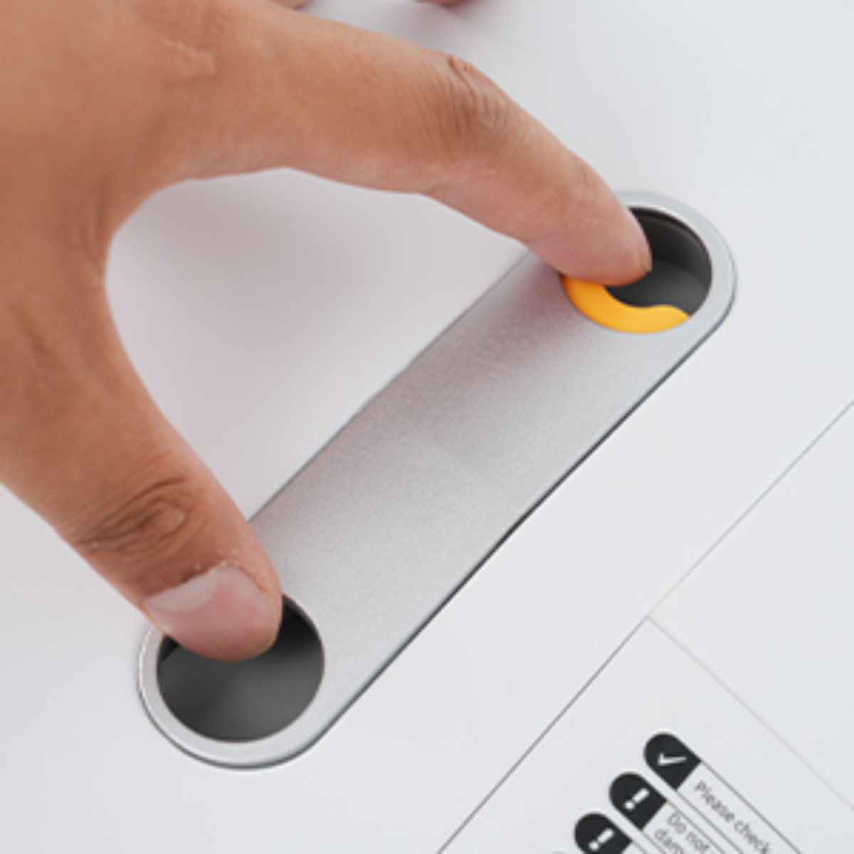 Eine Hand drückt eine gelbe Taste auf einem silbernen, elektronischen Gerät.