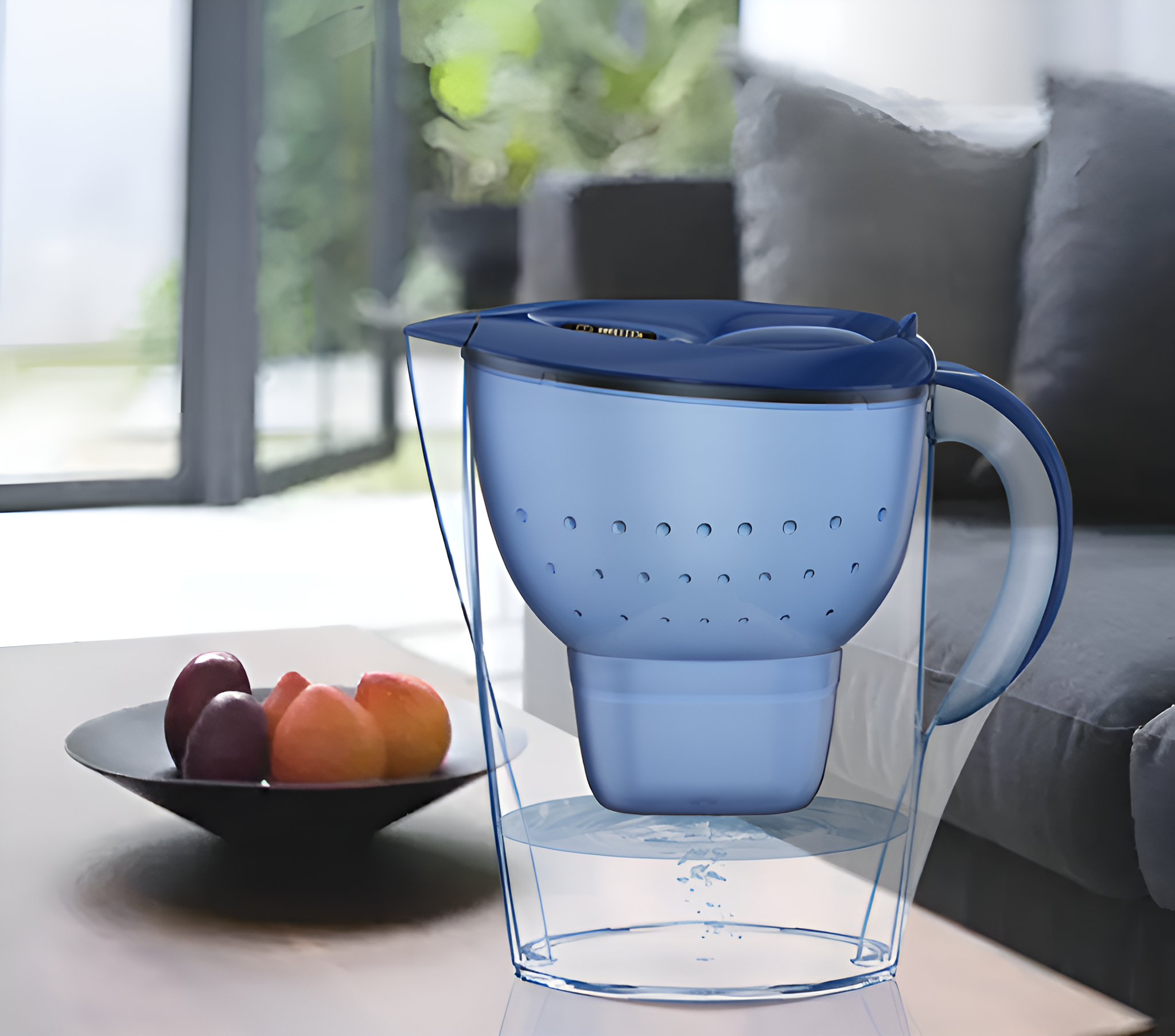 Ein blauer Wasserfilter-Krug mit Wasser und Früchten auf einem Tisch.