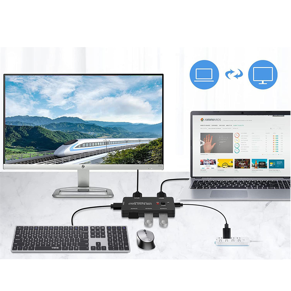 Ein Monitor, eine Tastatur, eine Maus und ein Laptop sind mit einem schwarzen Hub verbunden. Auf dem Monitor ist ein Zug zu sehen.