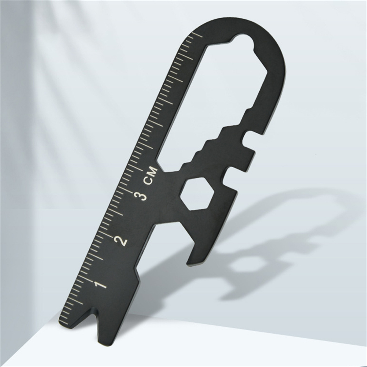 Ein schwarzes Multitool mit Lineal, Schraubenschlüssel und anderen Werkzeugen lehnt an einem hellen Hintergrund.