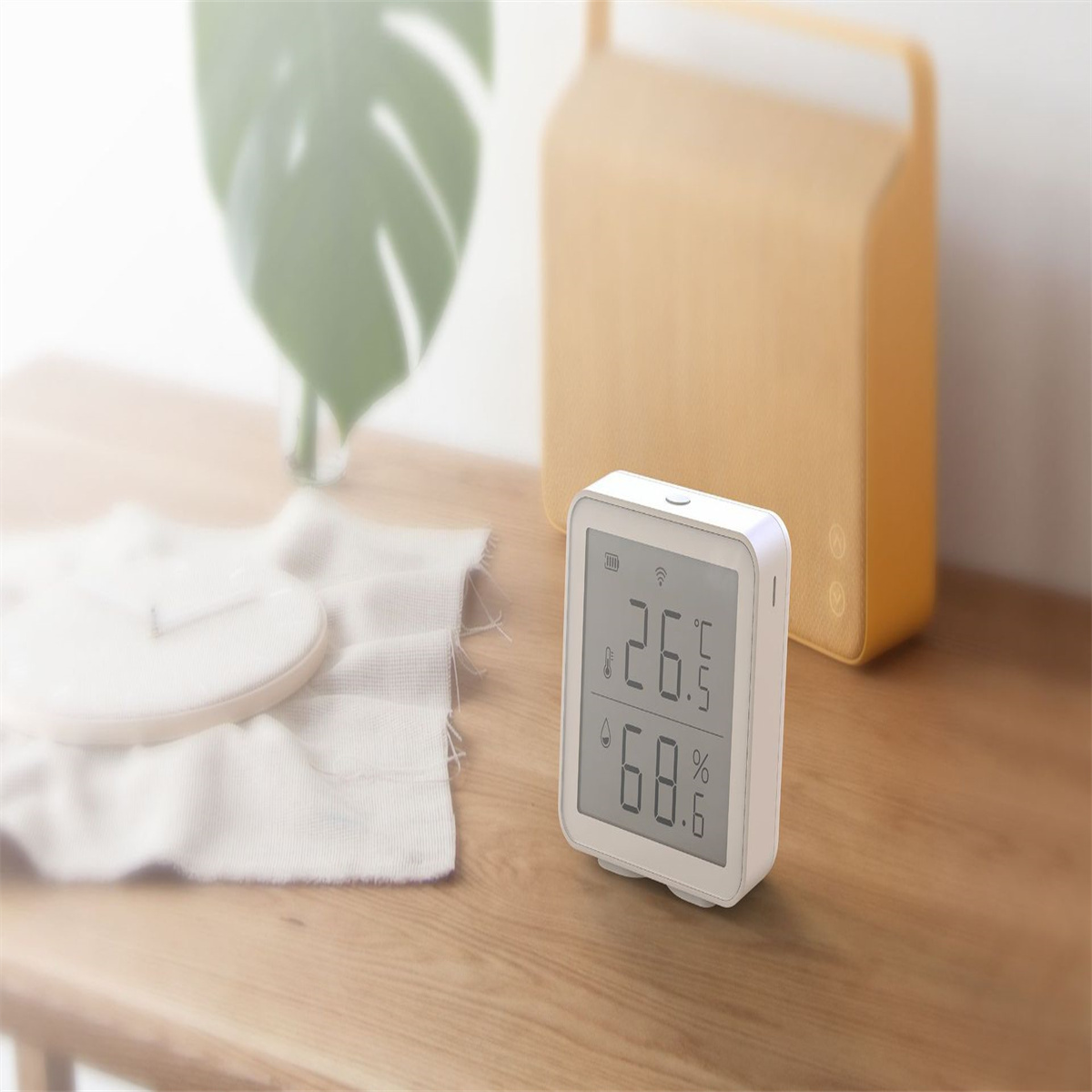 Weiße Digitaluhr mit Temperatur und Luftfeuchtigkeit. Auf Holztisch platziert.