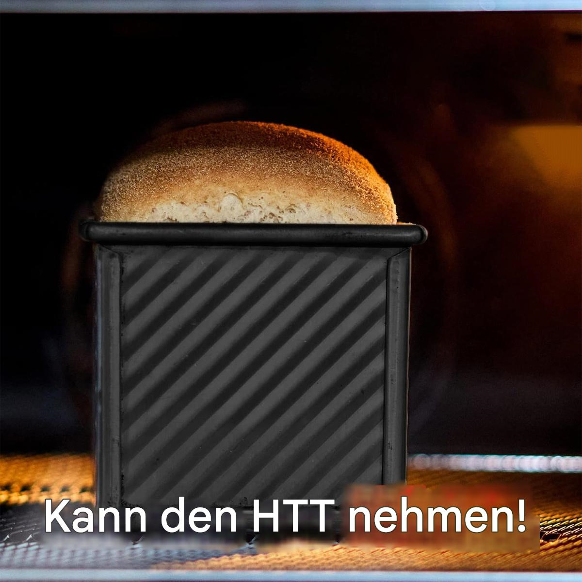 Brotlaib in einer schwarzen Brotform in einem Ofen. Dunkler Hintergrund.