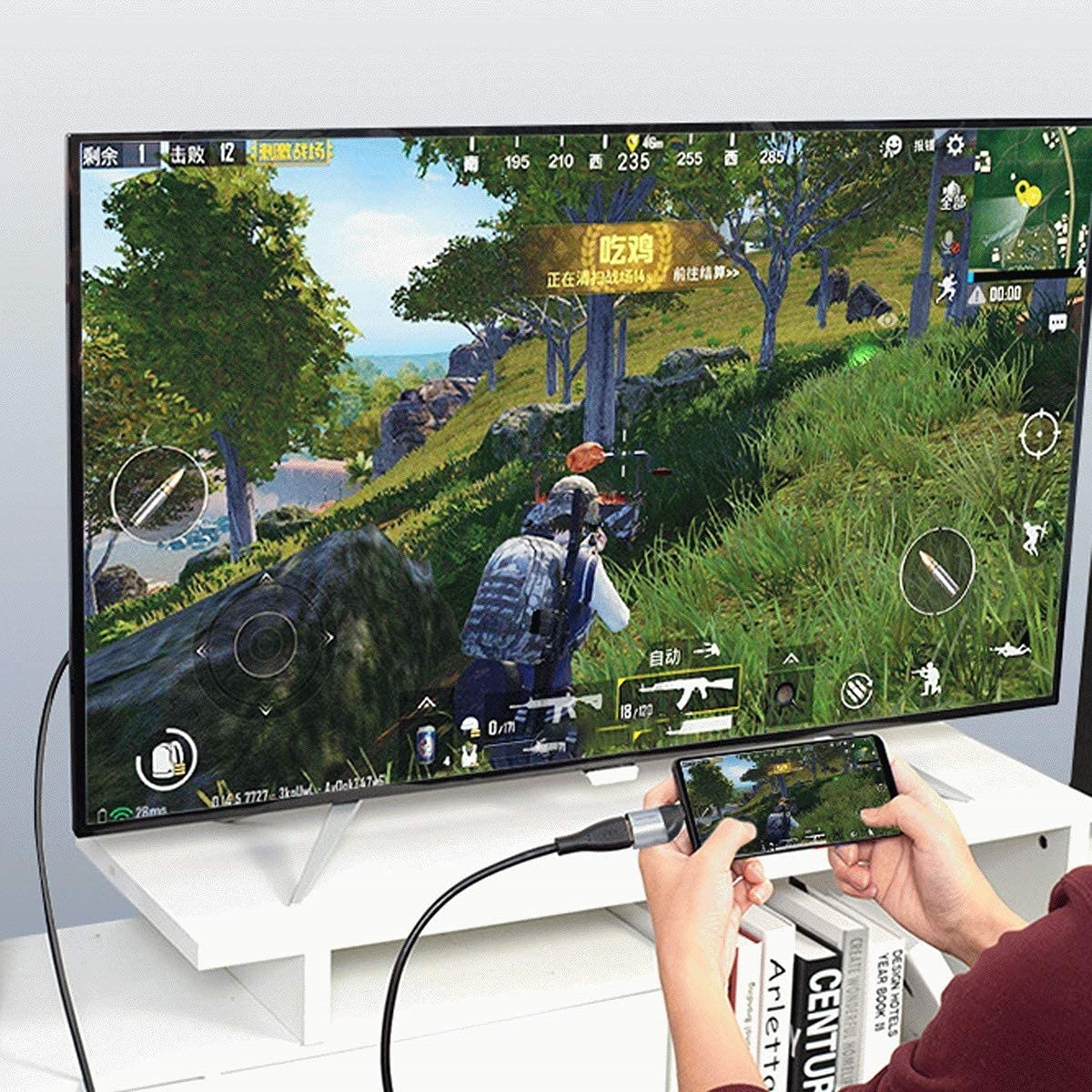 Mann spielt Spiel am Fernseher, verbunden mit Telefon. Spielbildschirm auf beiden.