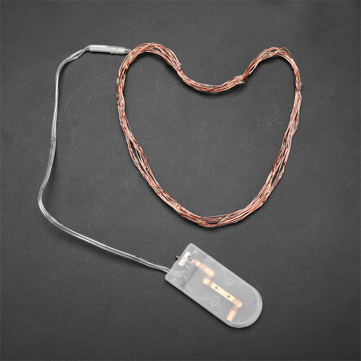 Eine Lichterkette aus Kupferdraht mit einem transparenten Kunststoff-Batteriegehäuse auf schwarzem Untergrund.