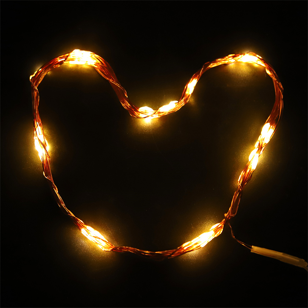 Kupferdrahtlichter in Herzform auf schwarzem Hintergrund, mit hellem, warmem gelben Glanz.
