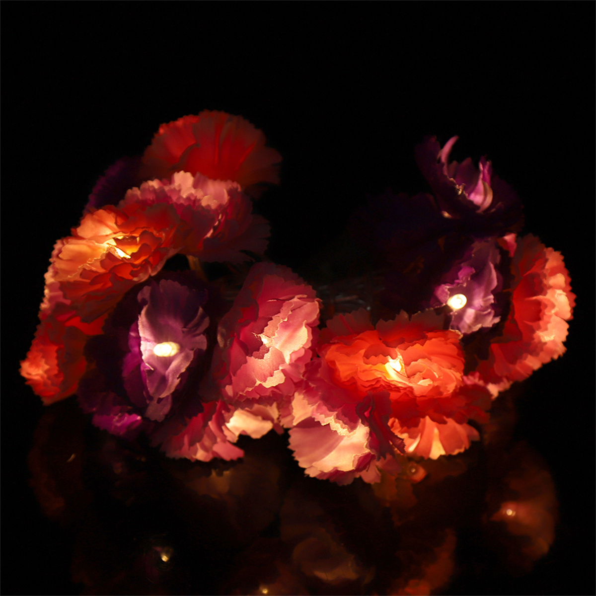 Eine Lichterkette mit bunten, beleuchteten Blumen auf dunklem Hintergrund.
