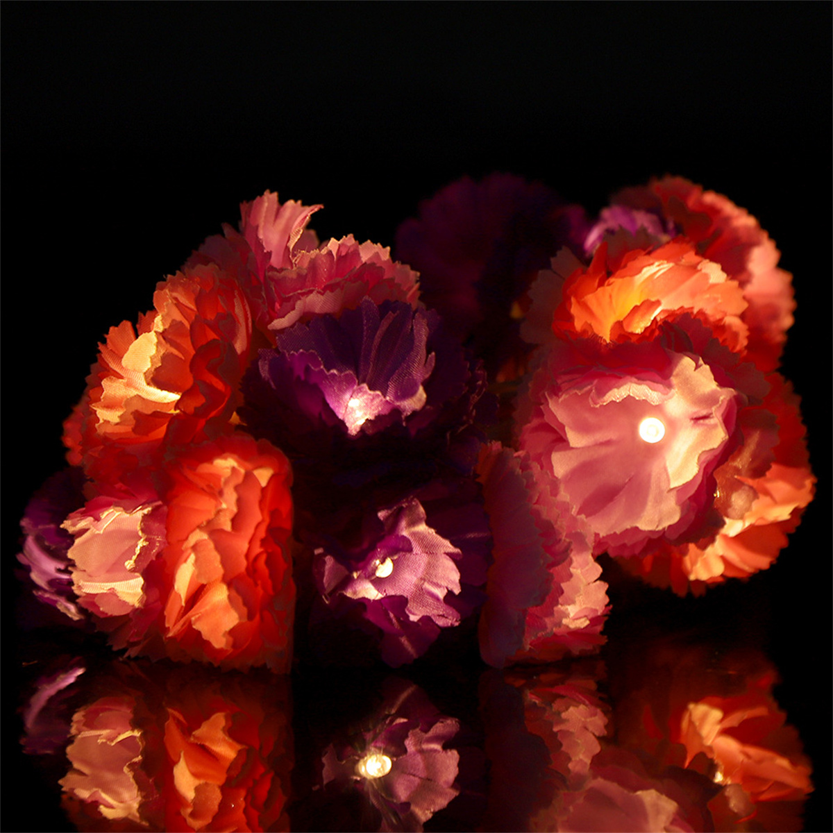 Ein Cluster bunter Kunstblumen auf schwarzem Hintergrund.