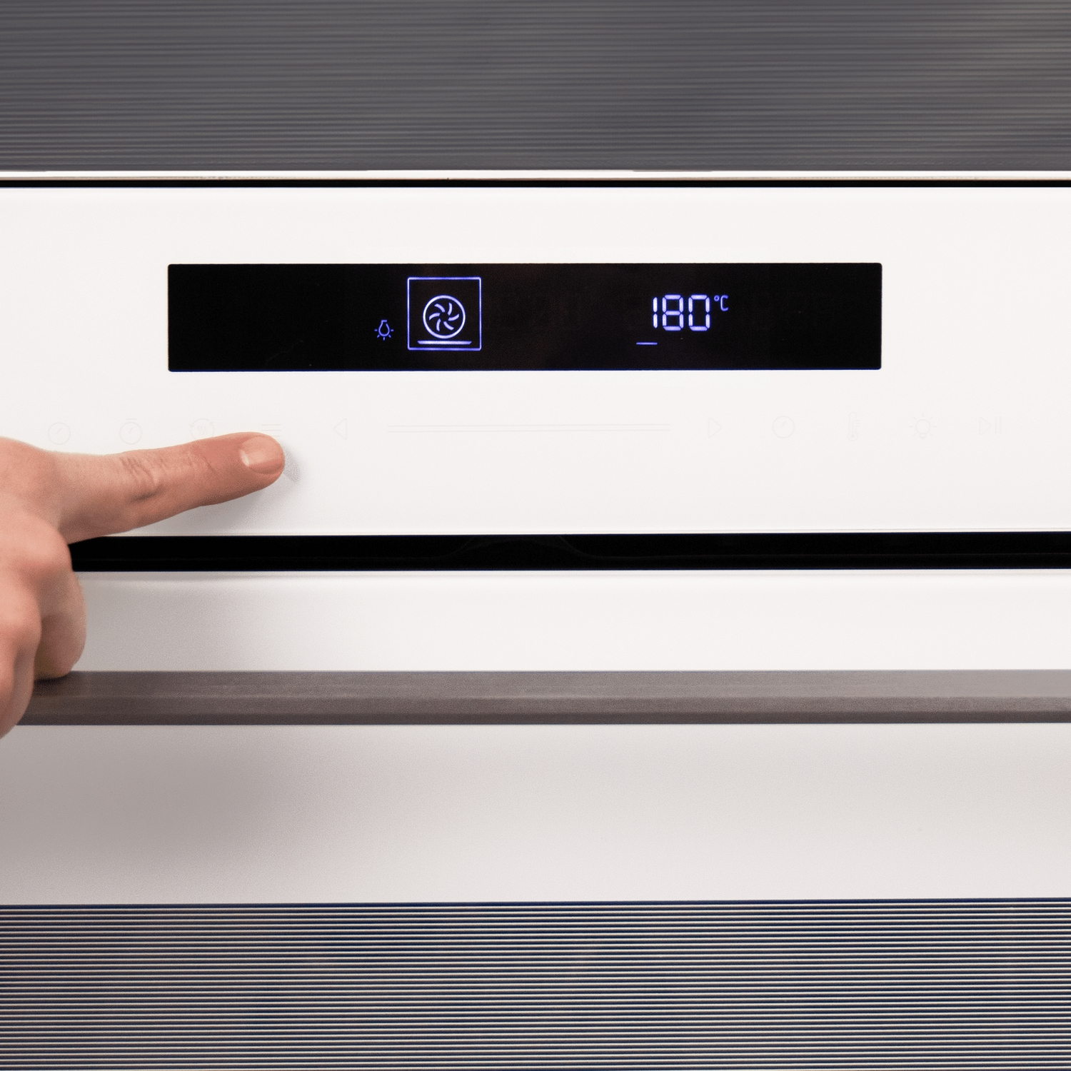 Una mano presionando el botón del ventilador de un horno blanco.