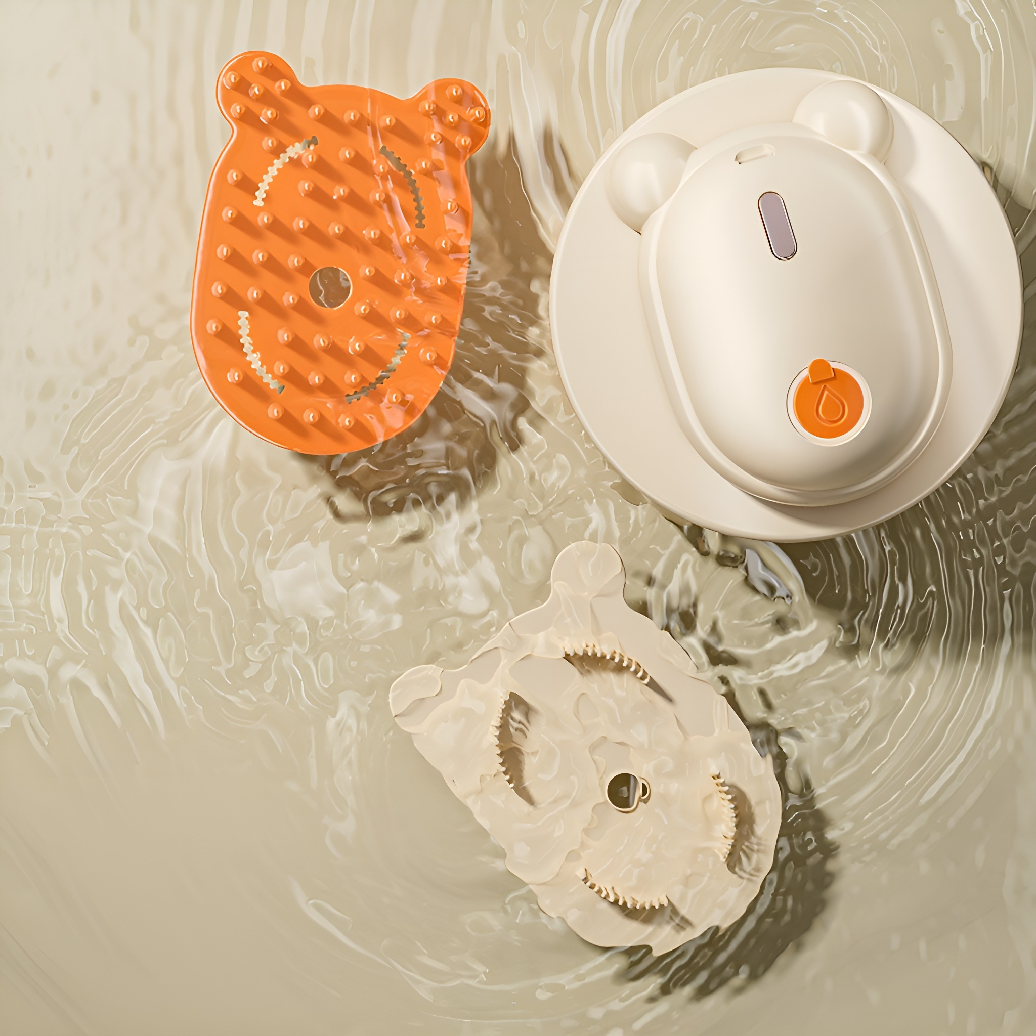 Drei Badeschrubber im Wasser, zwei orangefarbene, einer beige, alle bärenförmig mit strukturierten Oberflächen.