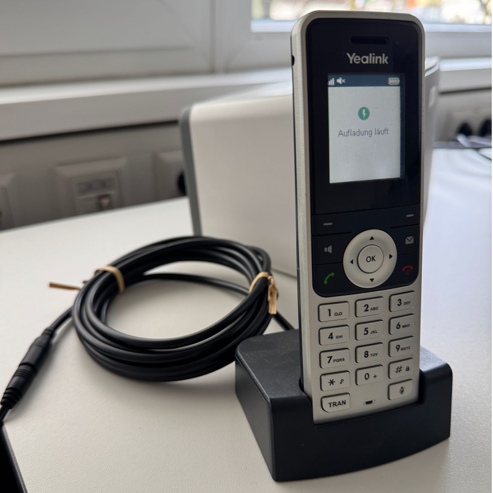 Yealink-Telefon auf Ständer mit Ladeanzeige und schwarzem Kabel.