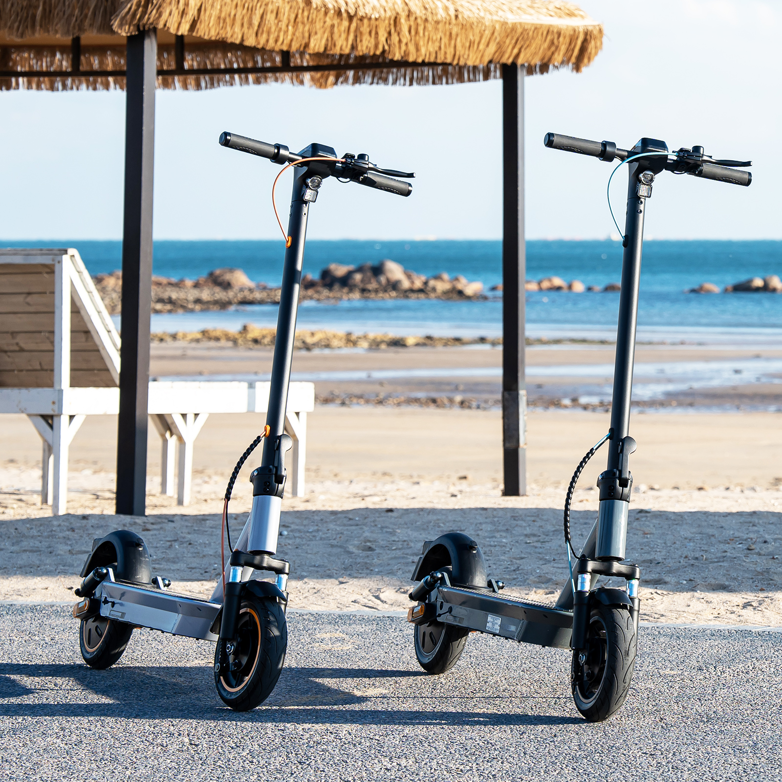Zwei schwarze und graue Roller an einem Strand. Ozean und Himmel im Hintergrund.