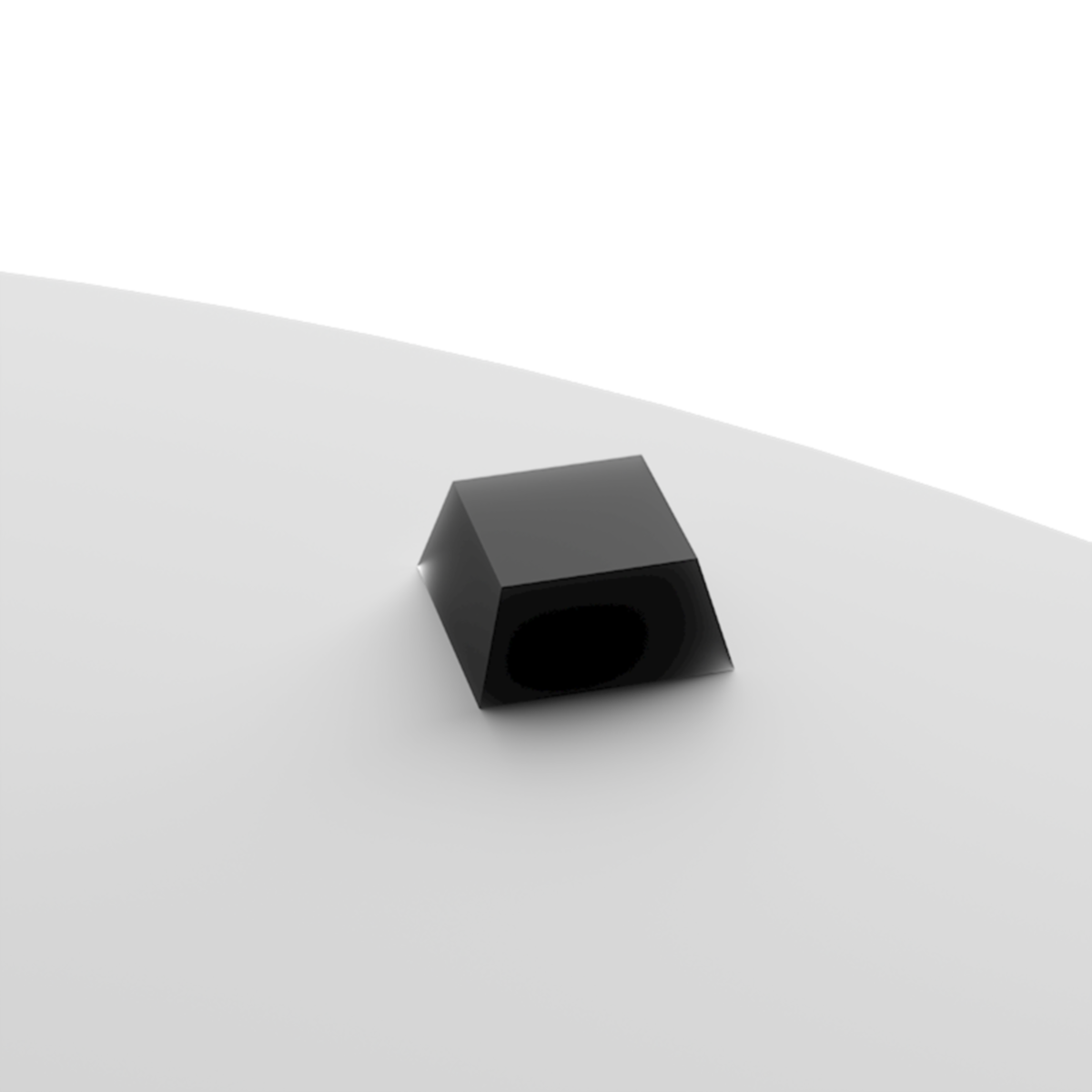 Een zwart, geometrisch object ligt op een wit oppervlak. Het lijkt een luidspreker of een vergelijkbaar apparaat te zijn.