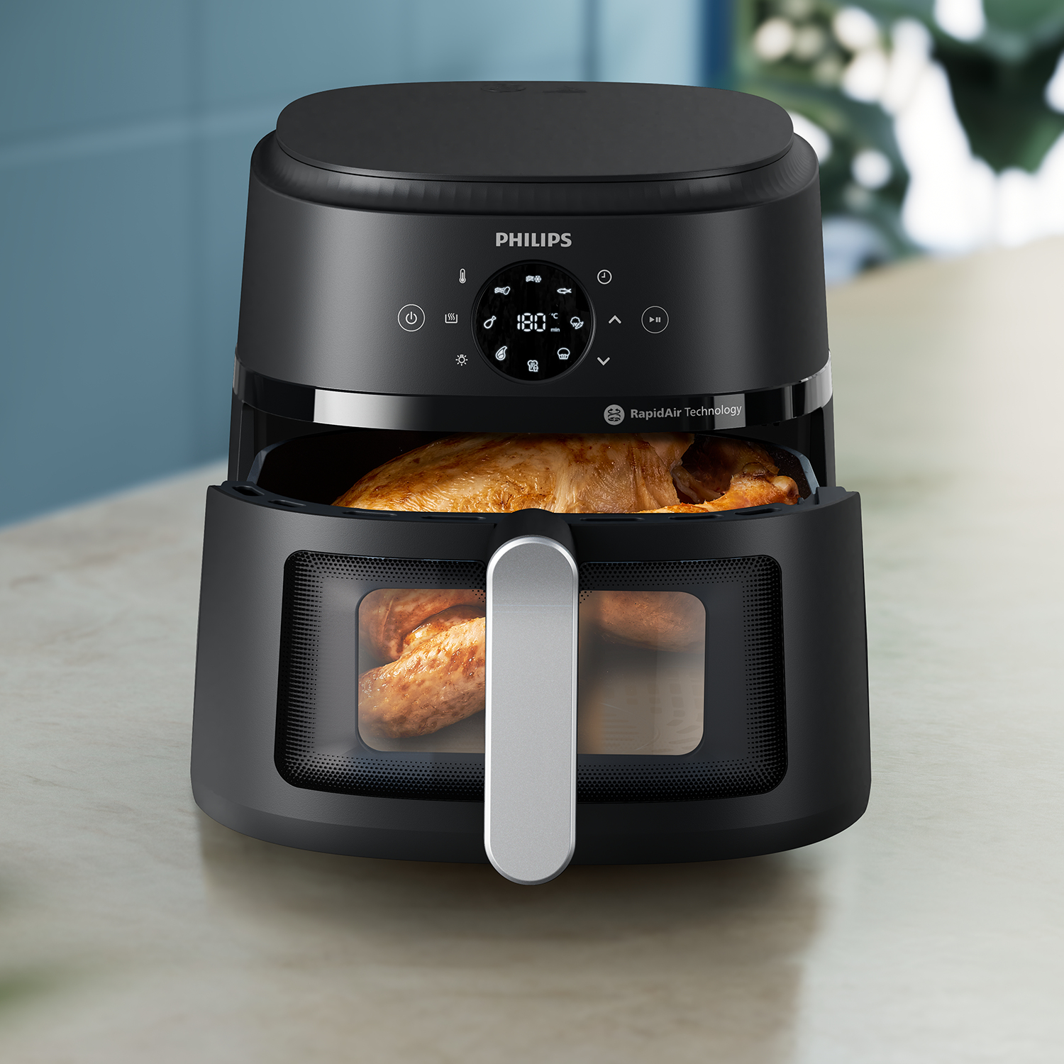 Friteuse à air noire avec poulet cuit visible. Marque Philips et technologie Rapid Air visibles.
