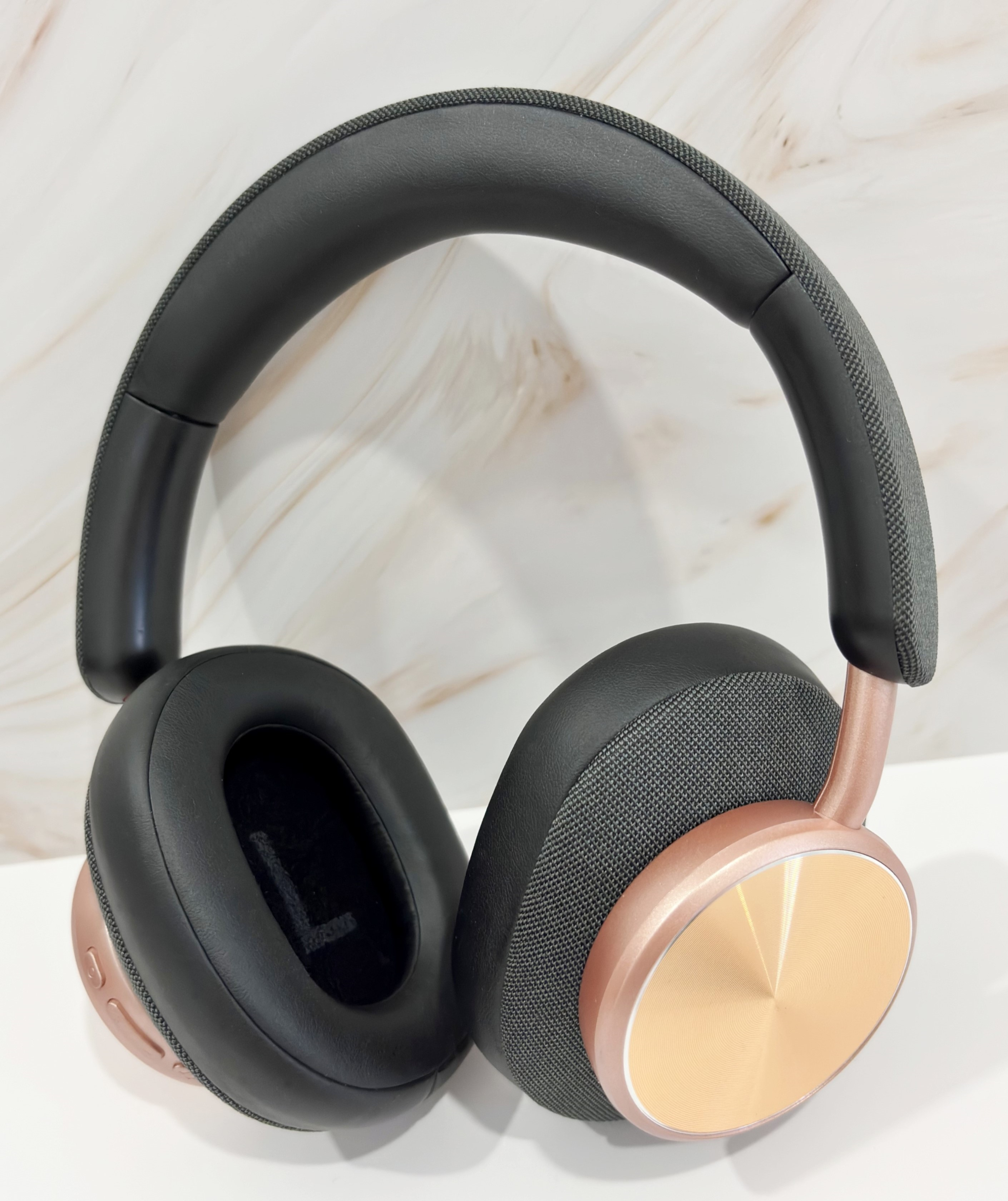 Auriculares inalámbricos con auriculares negros y un acento dorado rosa. La diadema es negra.