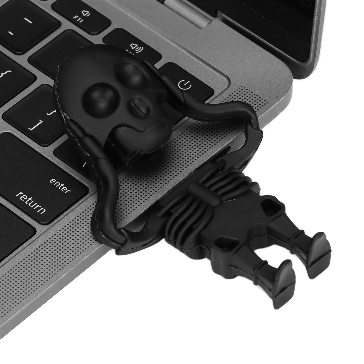 Schwarzer USB-Stick in Schädelform auf Laptop-Tastatur. Der Schädel ist mit einem Skelett verbunden.