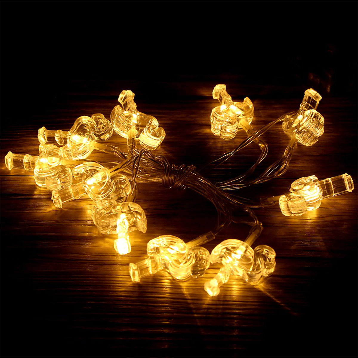 Eine Lichterkette mit gelben Lichtern in Form kleiner Wagen auf dunkler Holzoberfläche. Die Lichter leuchten.