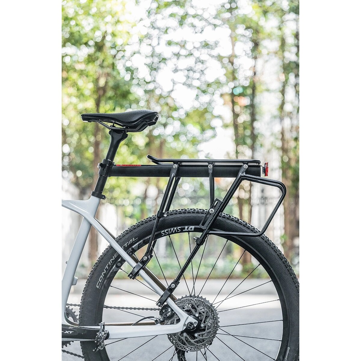 Portapacchi per bicicletta montato su una bici. Sfondo verde con alberi.