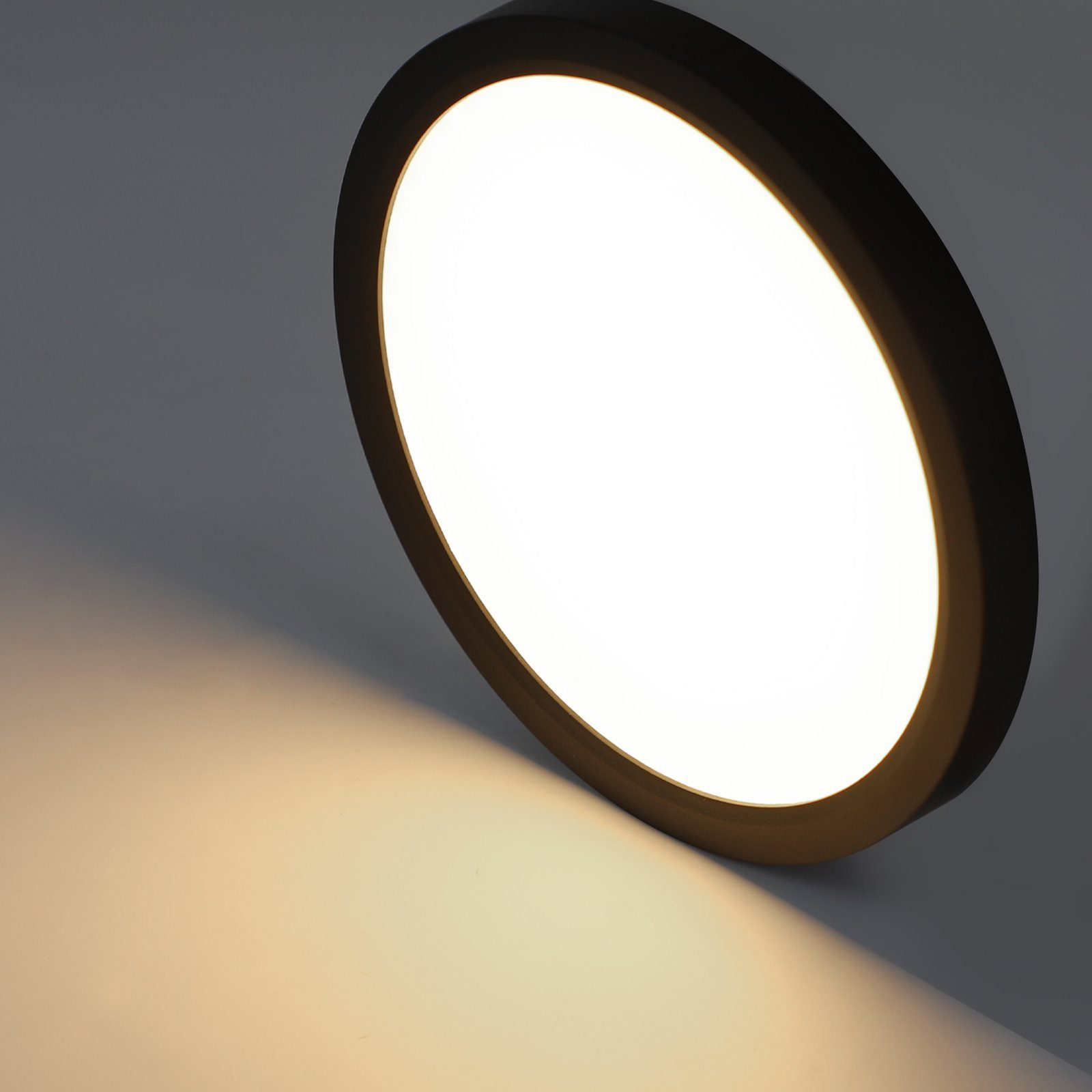 Okrągła, czarna, wpuszczana lampa sufitowa z jasnym, białym blaskiem.