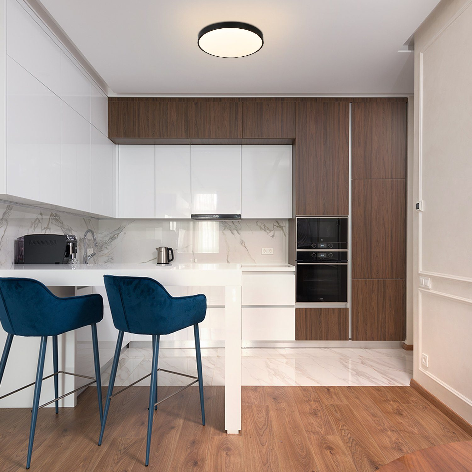 Nowoczesna kuchnia z białymi szafkami, brązowymi akcentami i dwoma niebieskimi stołkami barowymi. Widoczne jest światło sufitowe.