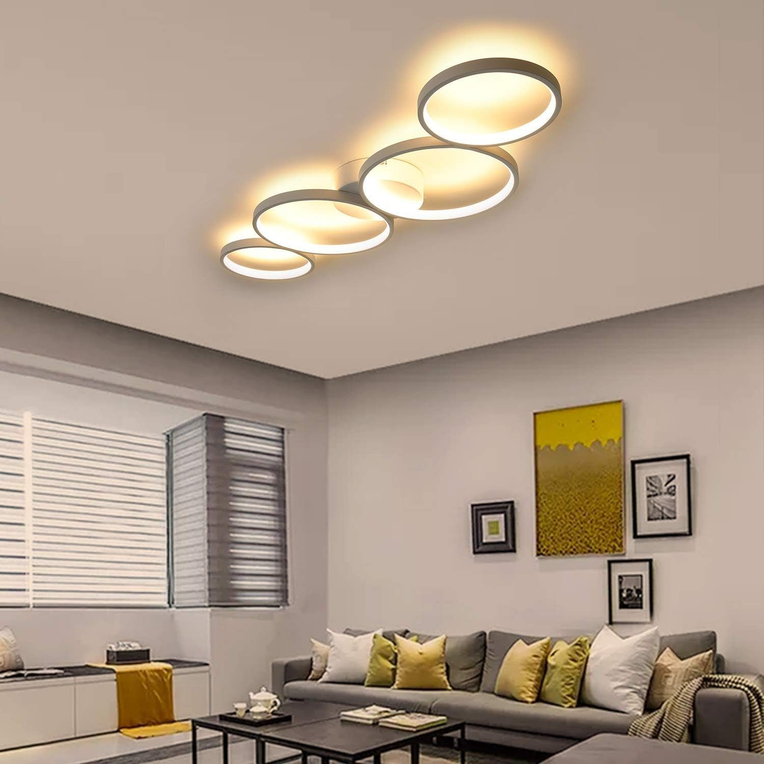 Lampy sufitowe o okrągłym kształcie, oświetlające salon z sofą, obrazami i dekoracjami.