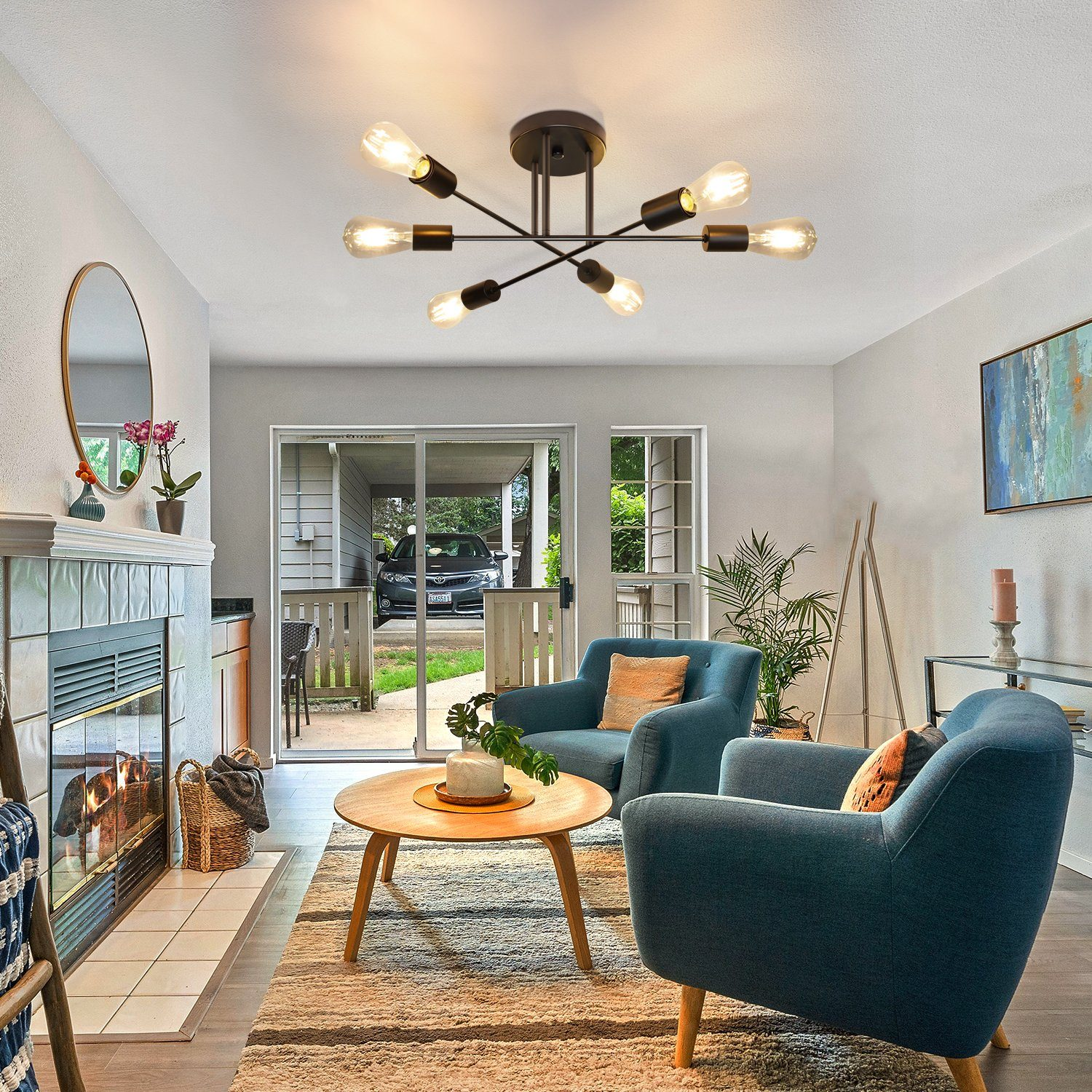 Salon z lampą sufitową, niebieskimi fotelami, stolikiem kawowym, kominkiem i przesuwanymi drzwiami szklanymi.