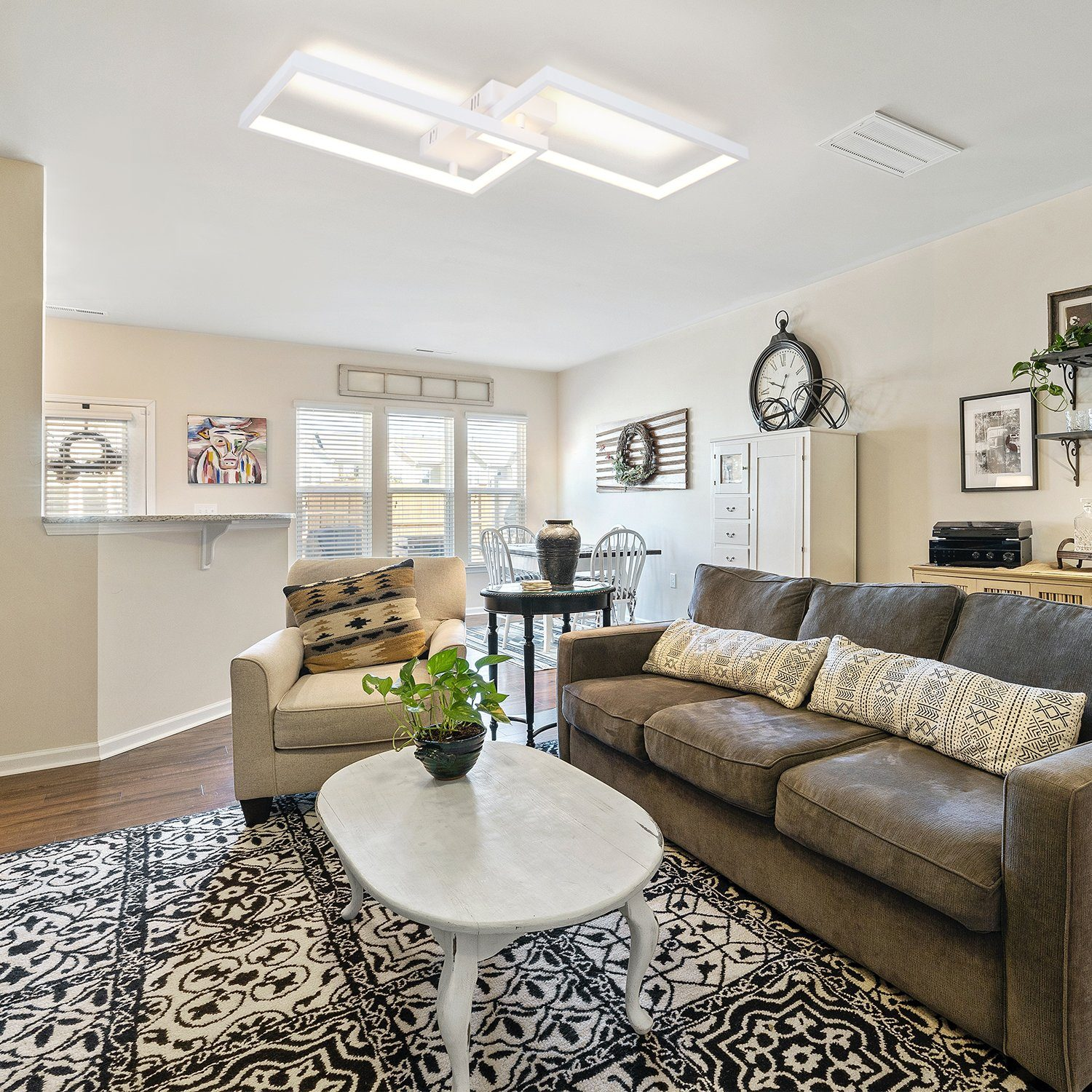 Salon z białymi lampami sufitowymi, sofą, fotelami, dywanem, stolikiem kawowym i różnymi elementami dekoracyjnymi.