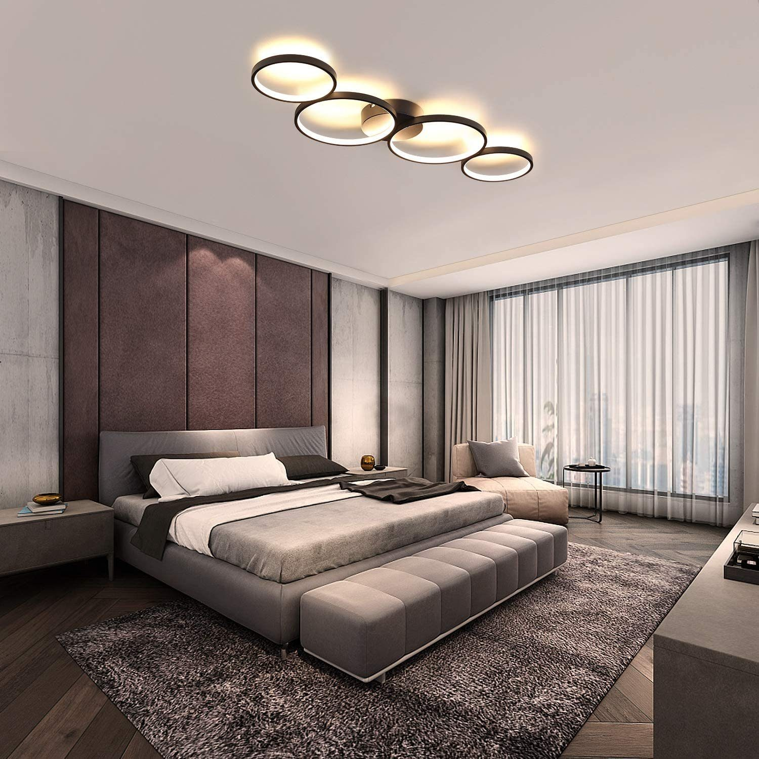 Interni camera da letto con letto e lampade a soffitto. Letto con lenzuola grigie, parete rosso scuro, luci soffitto rotonde.