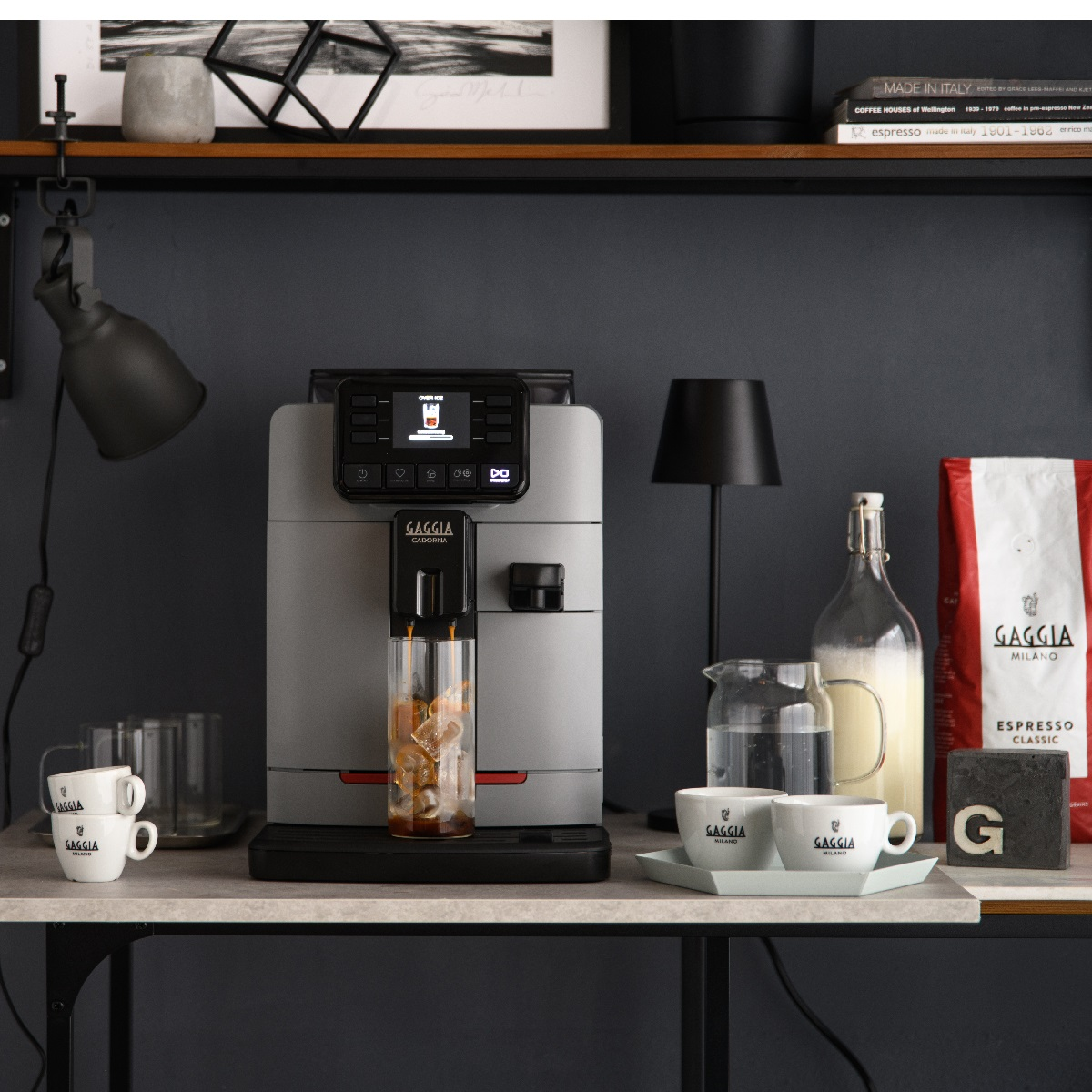 Kaffeemaschine mit Zubehör, darunter Tassen, eine Milchkanne und eine Kaffeetüte.
