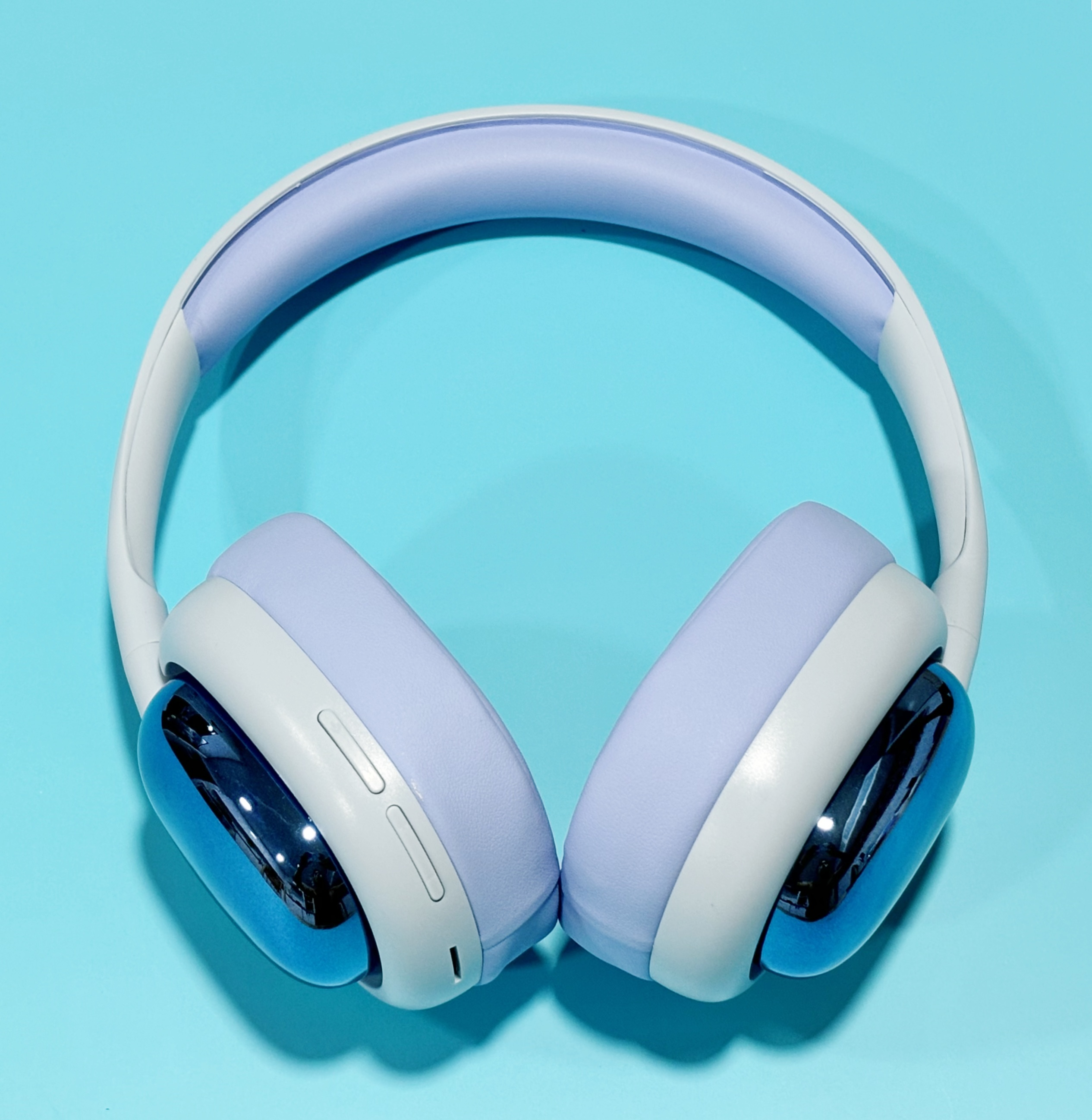 Auriculares supraaurales en blanco y morado claro, sobre fondo azul.