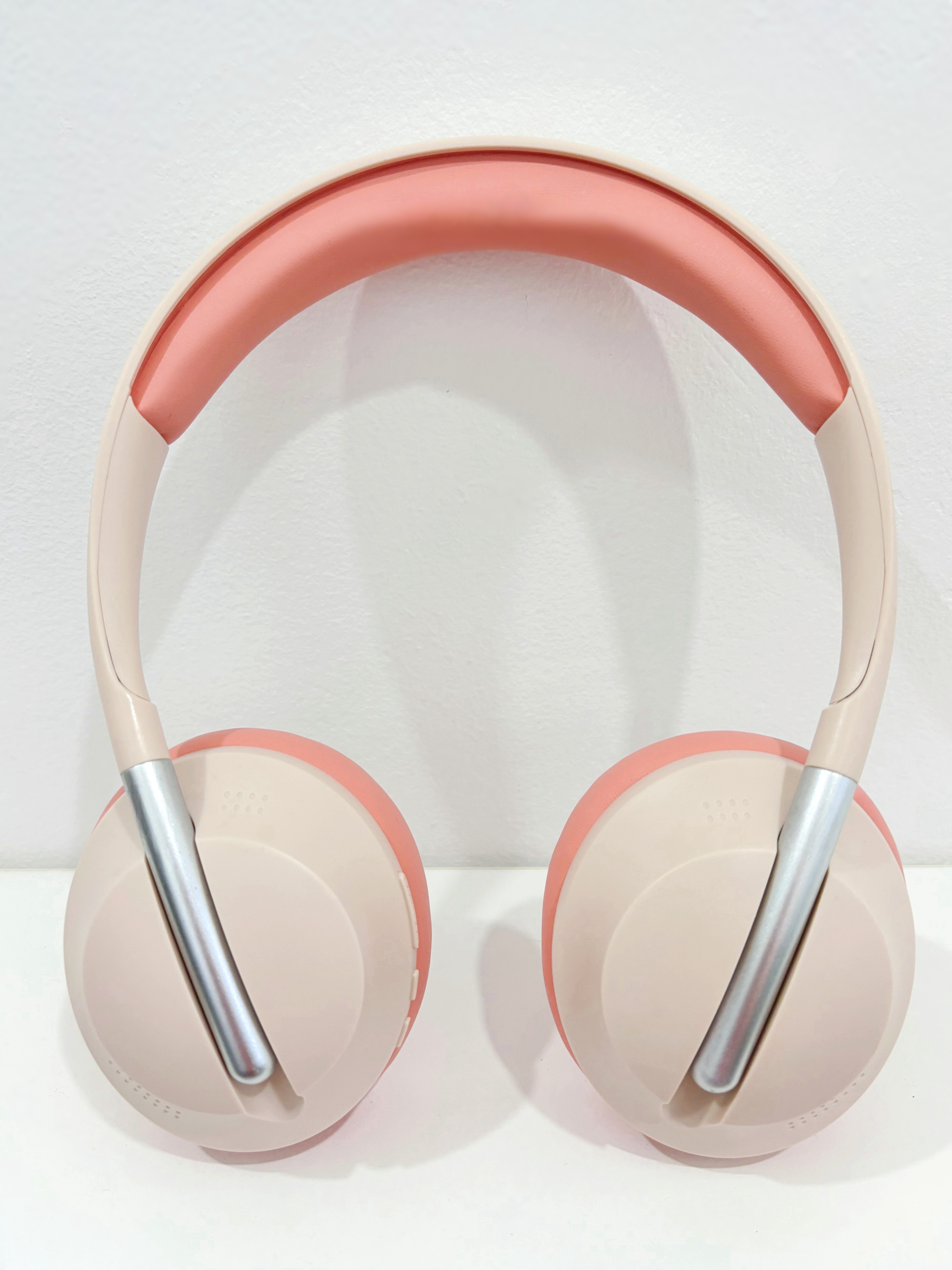 Auriculares beige y coral. La diadema es coral y los auriculares son beige.