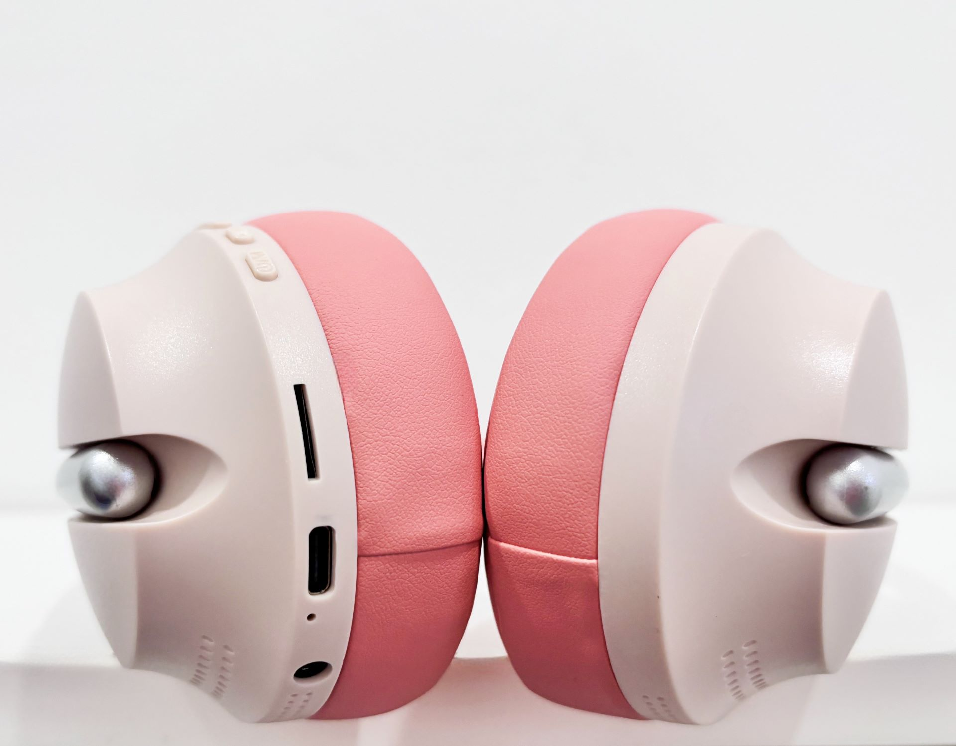 Par de auriculares rosas y beige. Acentos plateados en las copas. Fondo blanco.