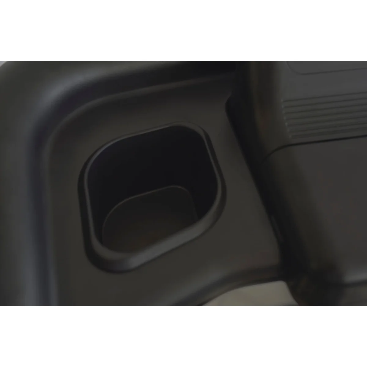 A close-up of a black cup holder on a black treadmill. It is an empty space.
