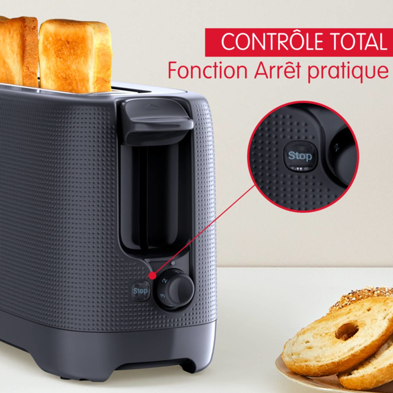 Zwarte broodrooster met toast, stopknop gemarkeerd, en bagels op de voorgrond.