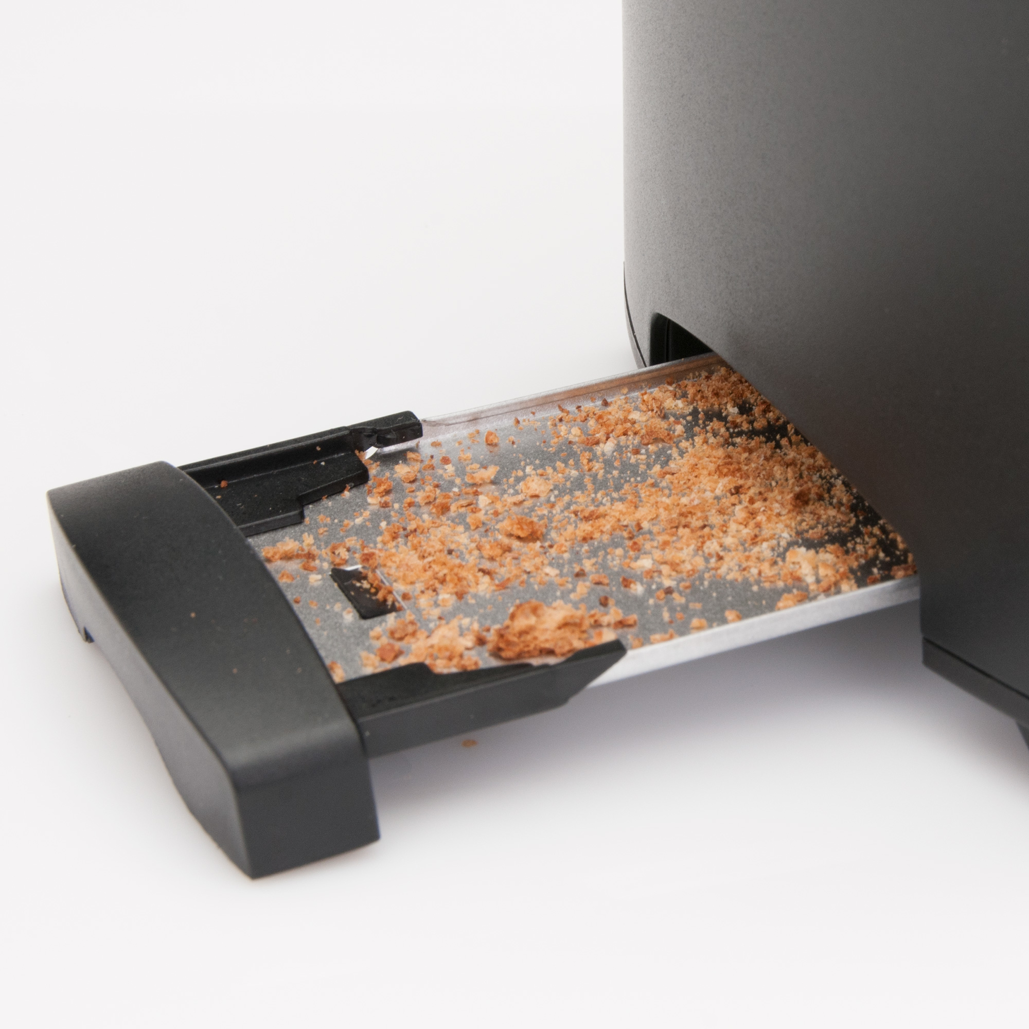 Nahaufnahme eines schwarzen Toasters mit einem Krümelbehälter voller Krümel, auf weißem Hintergrund.