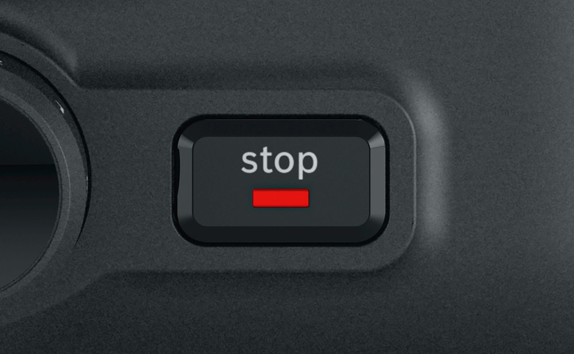 Zbliżenie czarnego przycisku ze słowem 'stop' w kolorze białym i czerwonym paskiem poniżej.