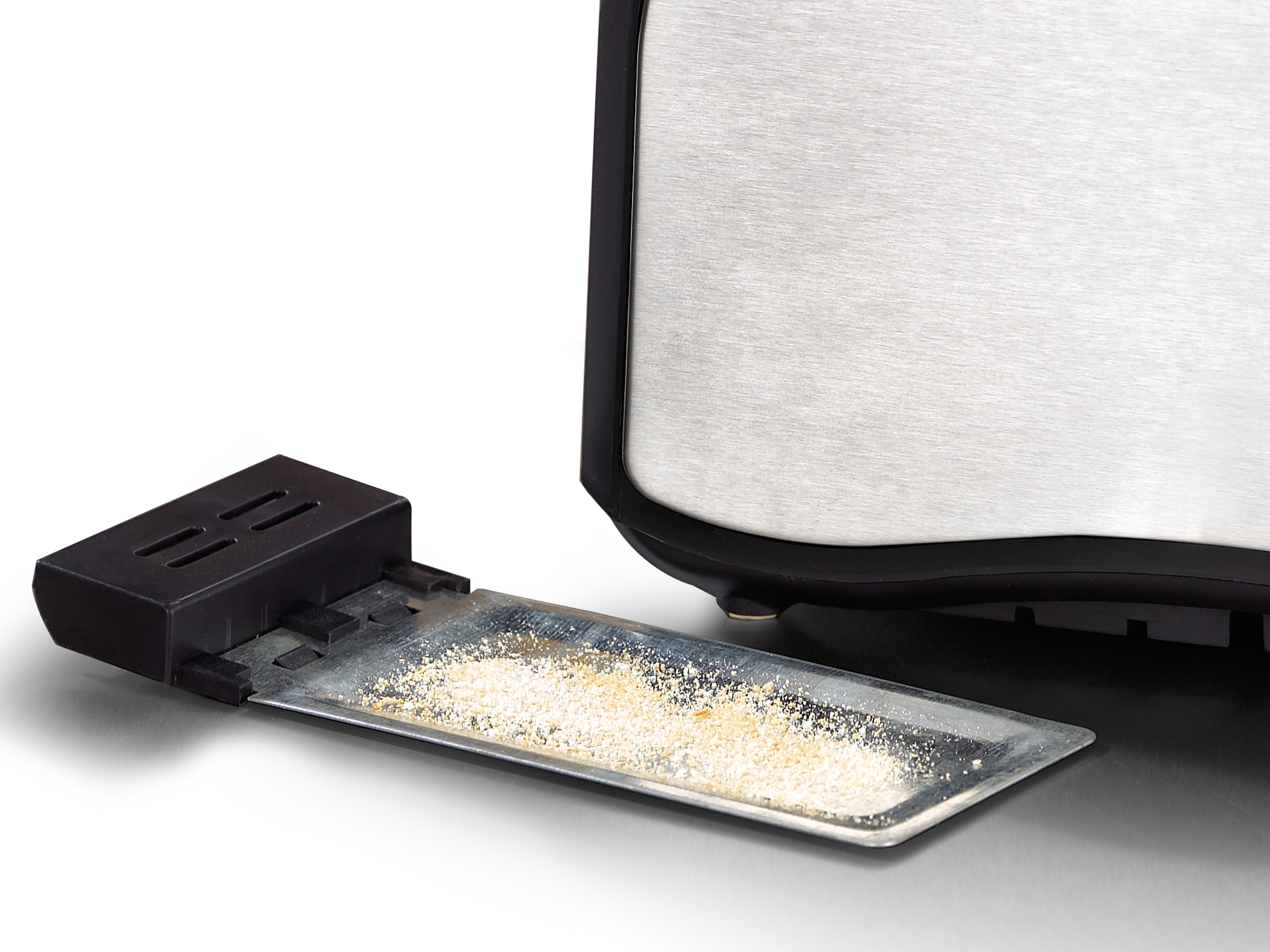 Krümelschublade mit Brotkrümeln, neben einem silbernen Toaster.