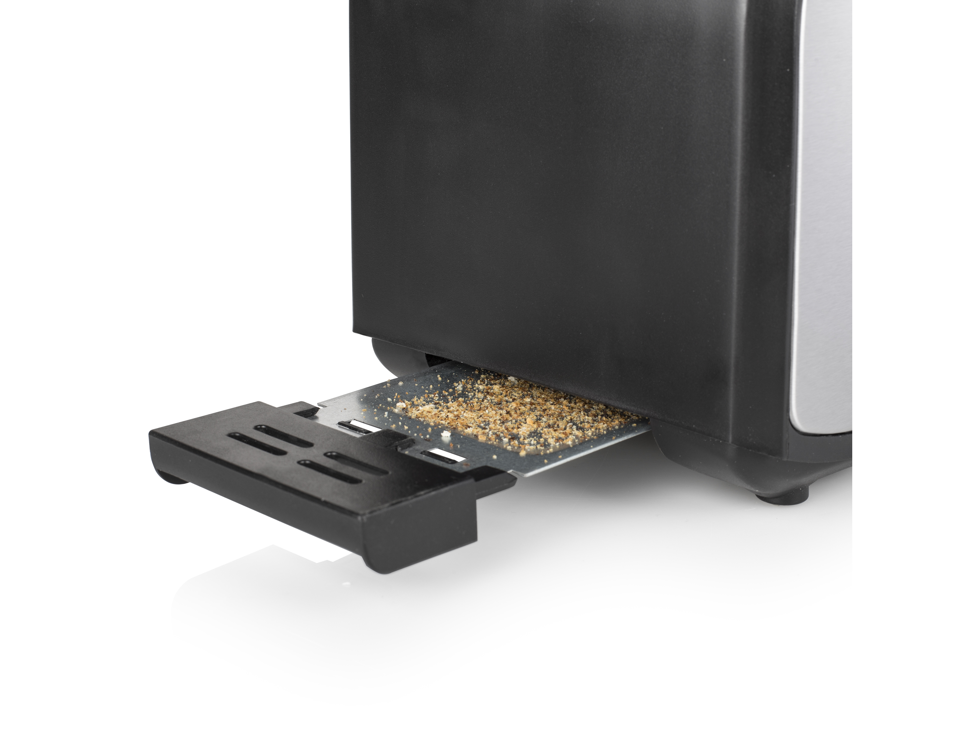 Nahaufnahme der Krümelschublade eines Toasters, Krümel sichtbar, schwarzer Hintergrund.