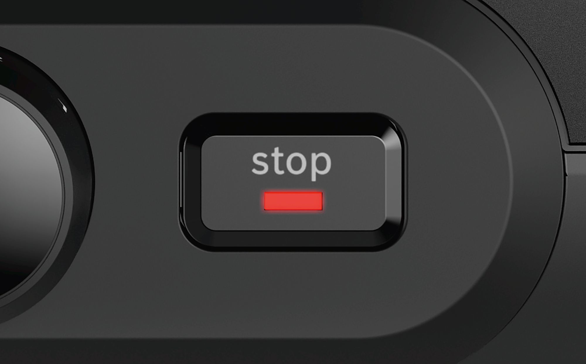 Zbliżenie czarnego przycisku ze słowem „stop” na biało i czerwonym światłem.