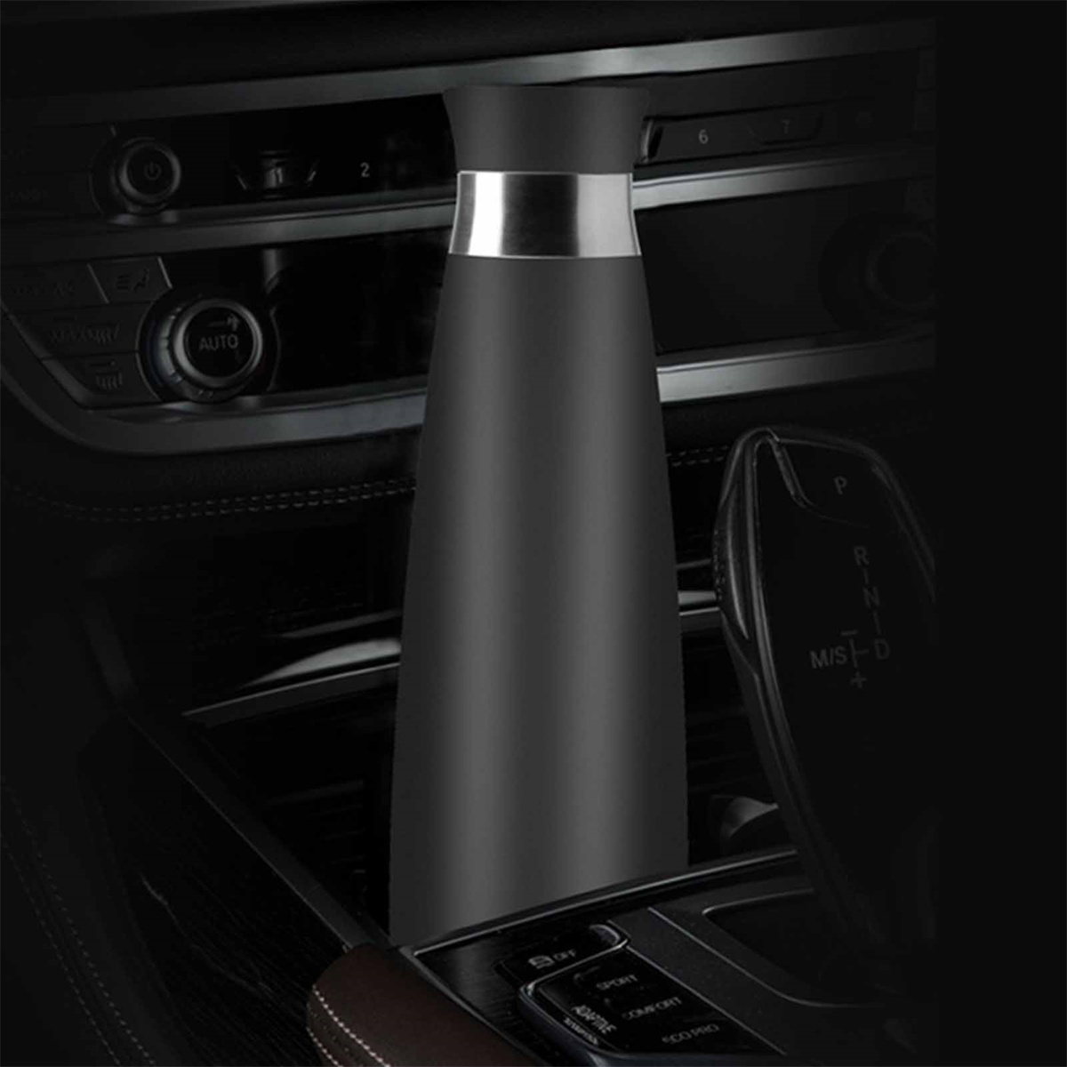 Schwarze Thermosflasche im Mittelkonsolenbereich eines Autos.