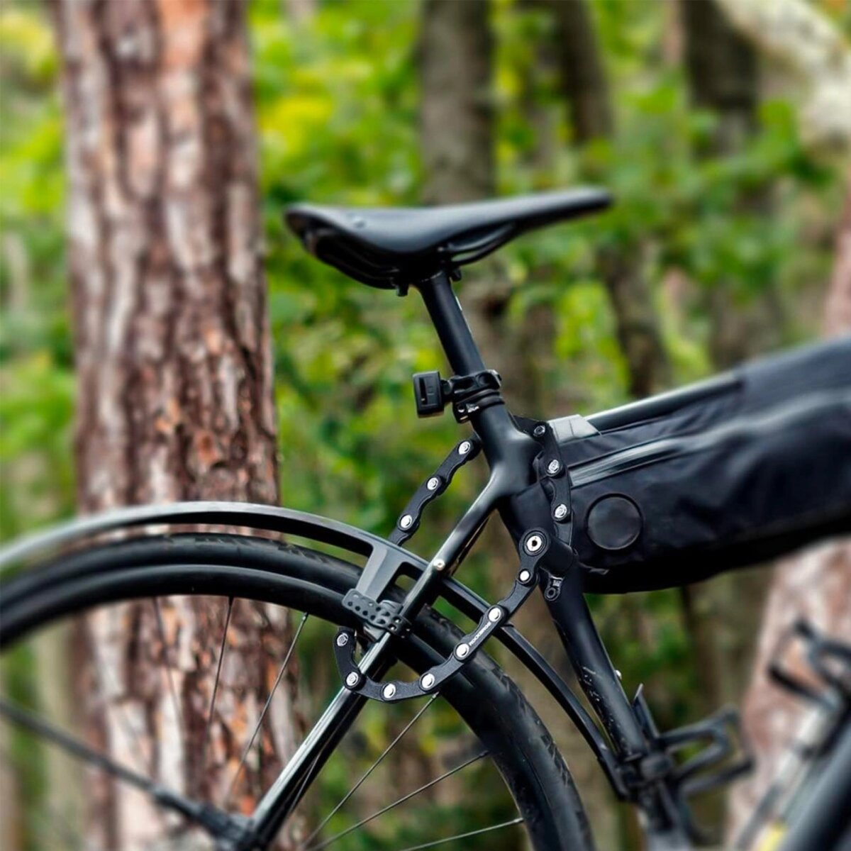 Schwarzes Fahrrad mit Schloss. Bäume im Hintergrund. Nahaufnahme des Schlosses und der Fahrradteile.