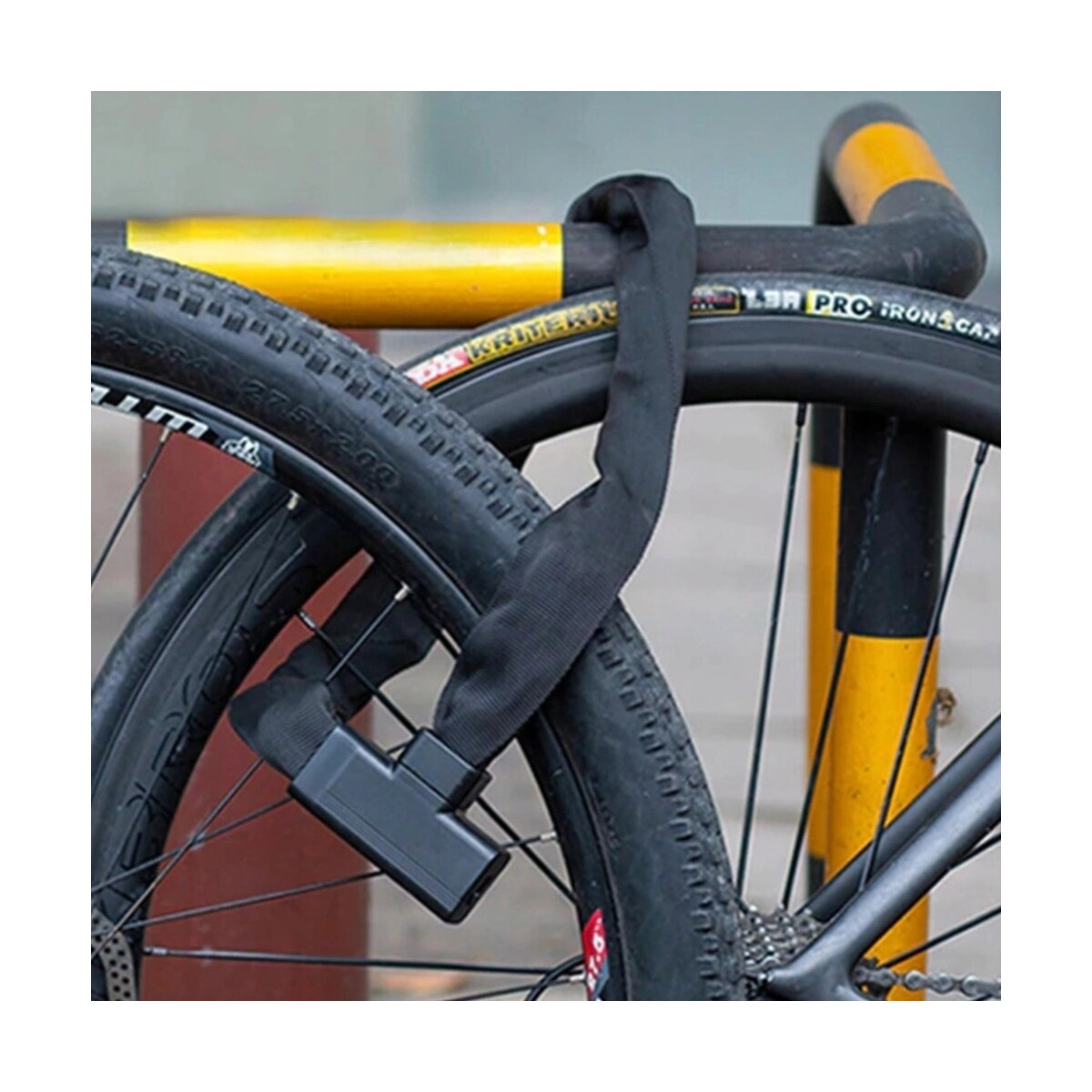 Un lucchetto nero per bicicletta avvolto attorno a un palo di metallo giallo. Una bici è visibile in primo piano.