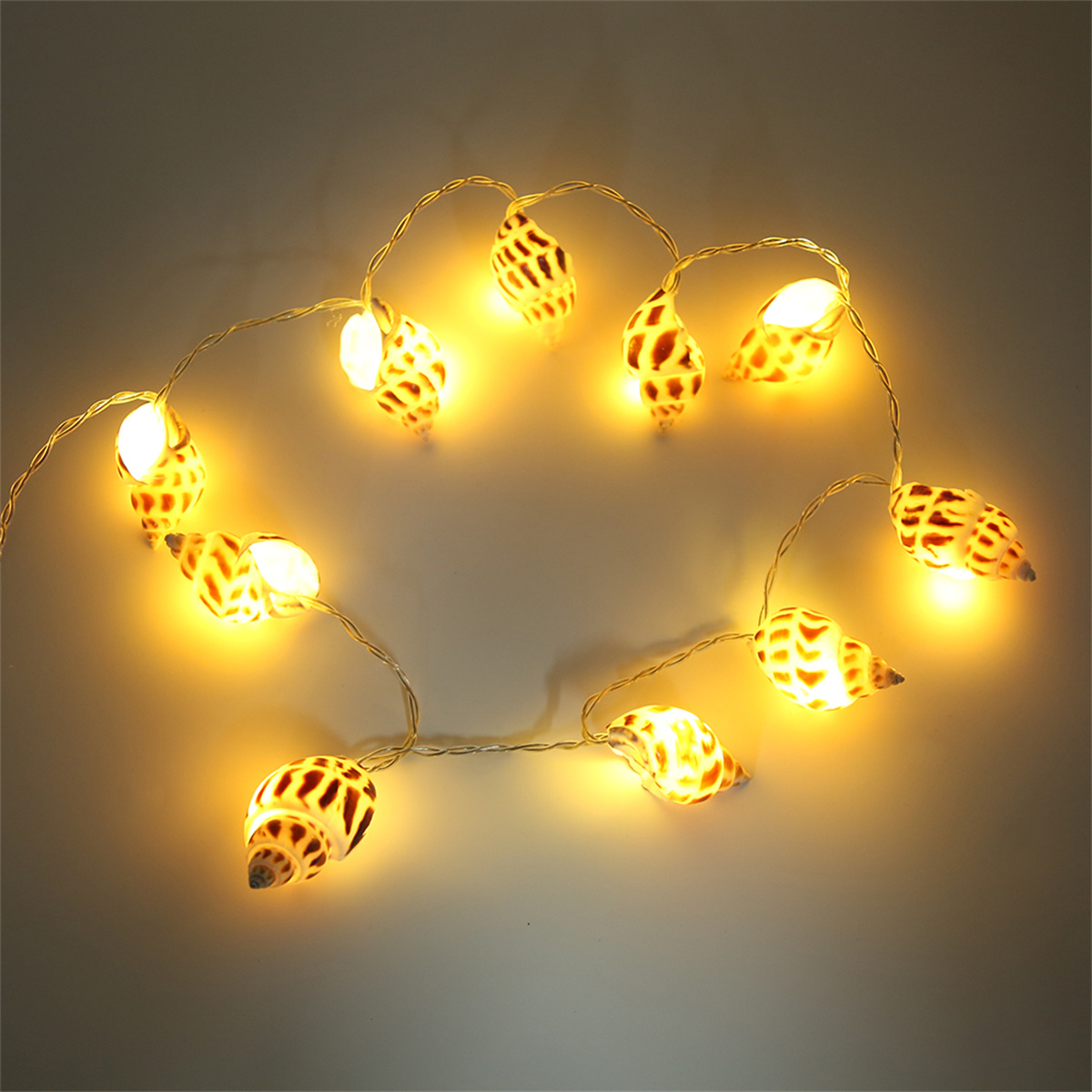 Eine Lichterkette mit Muschellichtern vor dunklem Hintergrund, mit warmgelben Lichtern.