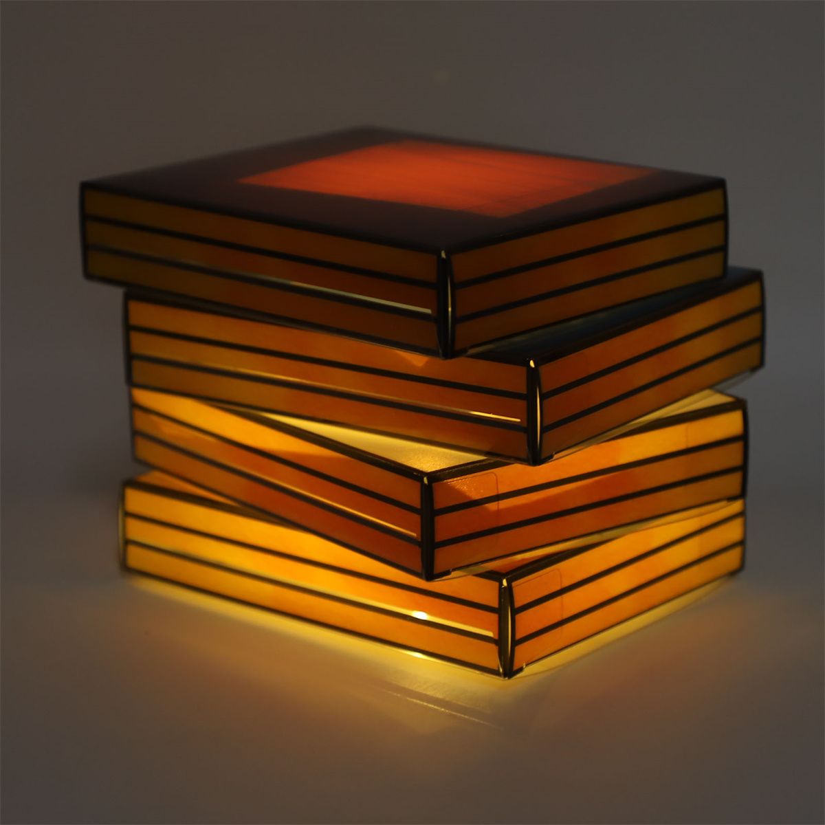Vier beleuchtete Boxen gestapelt. Jede Box gibt Licht ab. Die oberste Box ist orange.