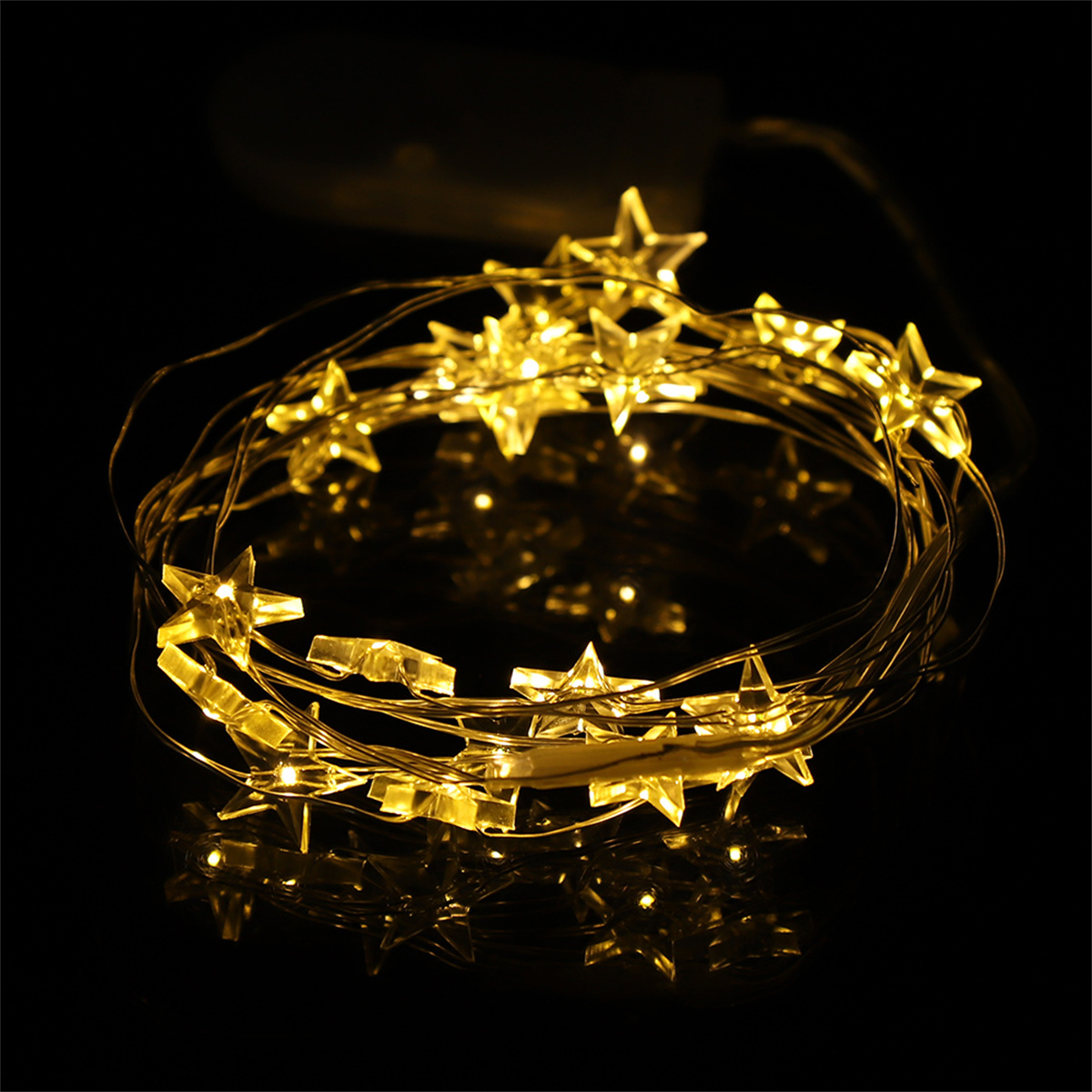 Lichterkette aus gelben sternförmigen Lichtern auf schwarzem Untergrund. Die Sterne leuchten und erzeugen ein Leuchten.