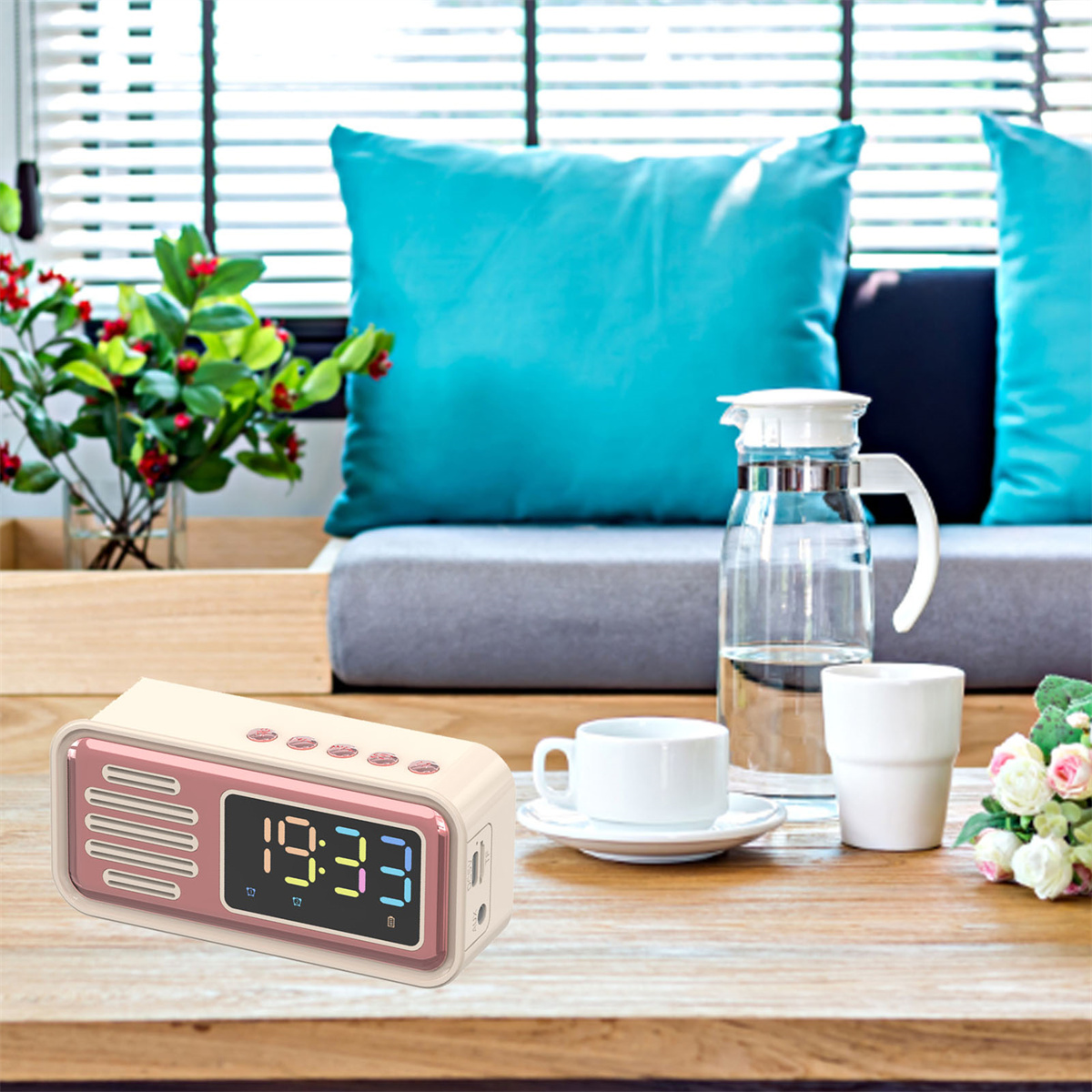 Radiowecker auf einem Tisch mit Tasse, Blumen und Kissen im Hintergrund.