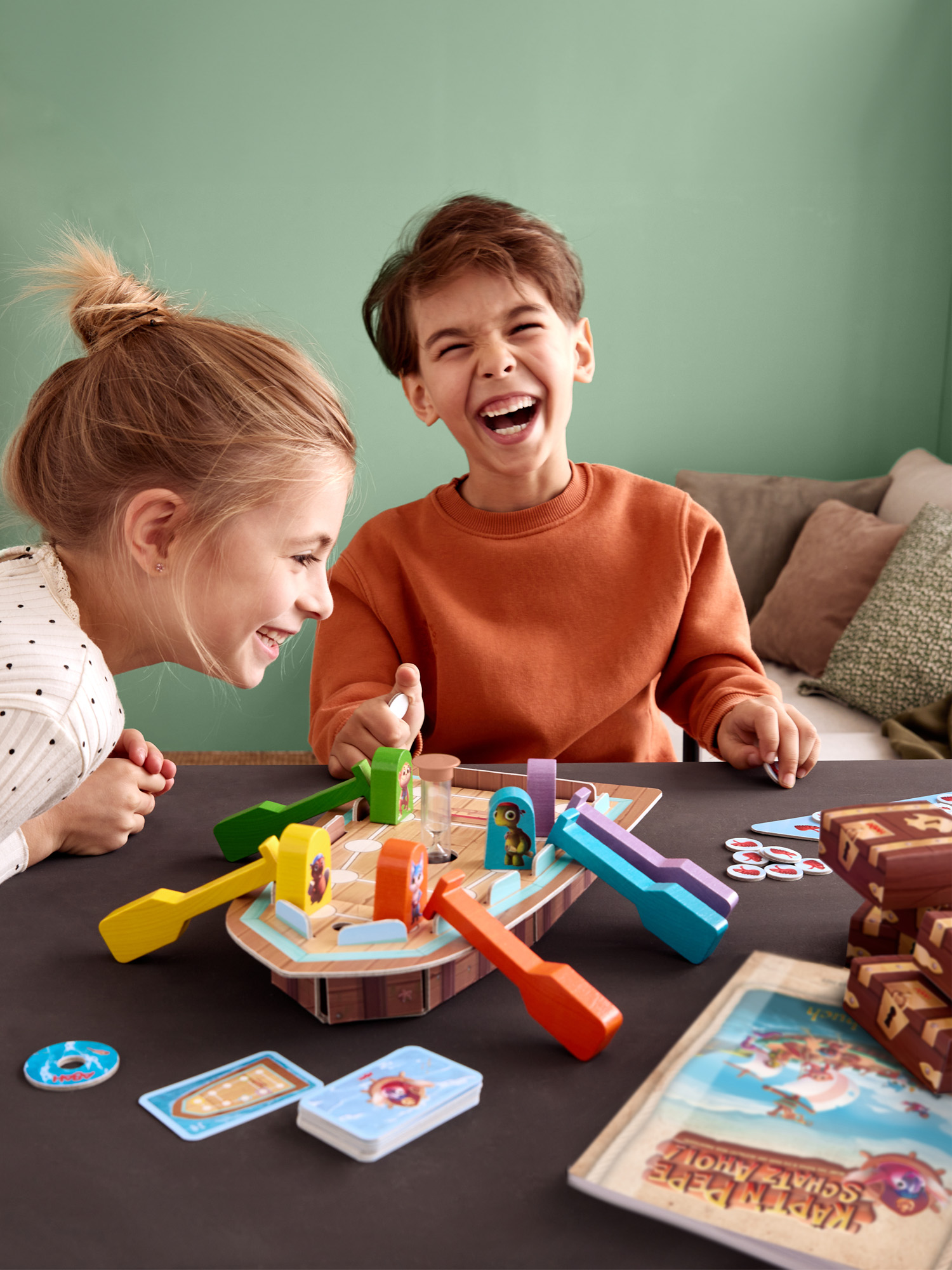 Zwei Kinder spielen Brettspiel am Tisch, lachen.